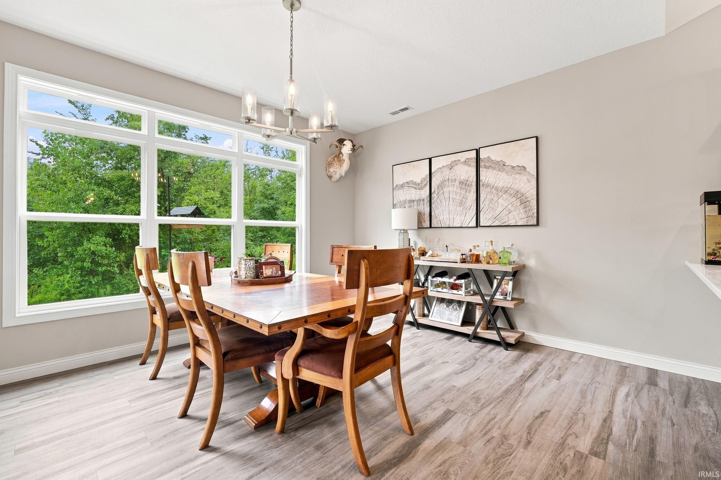 Expansive multi-pane window, wood-finish flooring, recessed lighting, and a contemporary chandelier