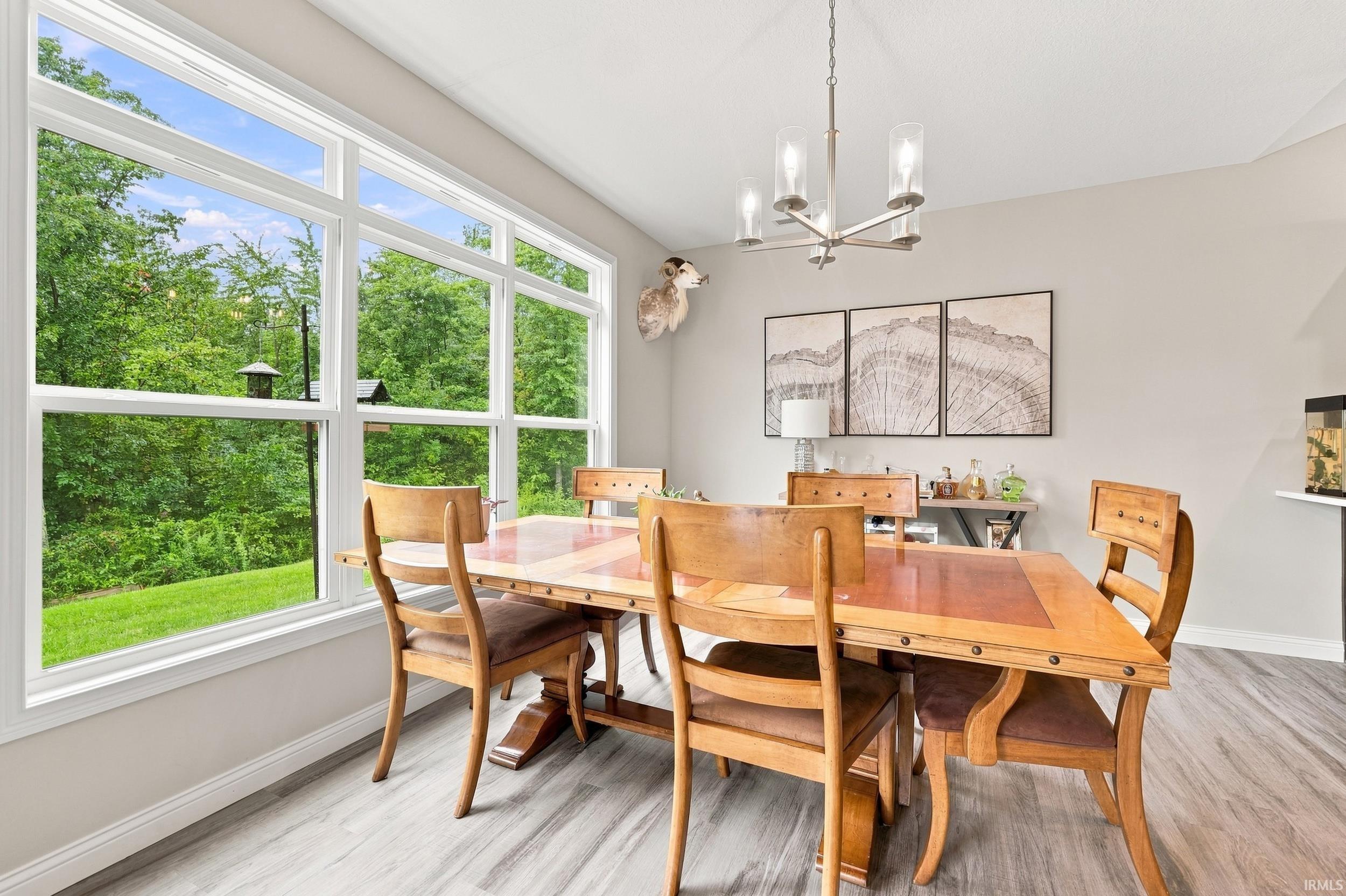 Expansive window offering abundant natural light, brushed nickel chandelier, light gray wall color, and wood-finish flooring