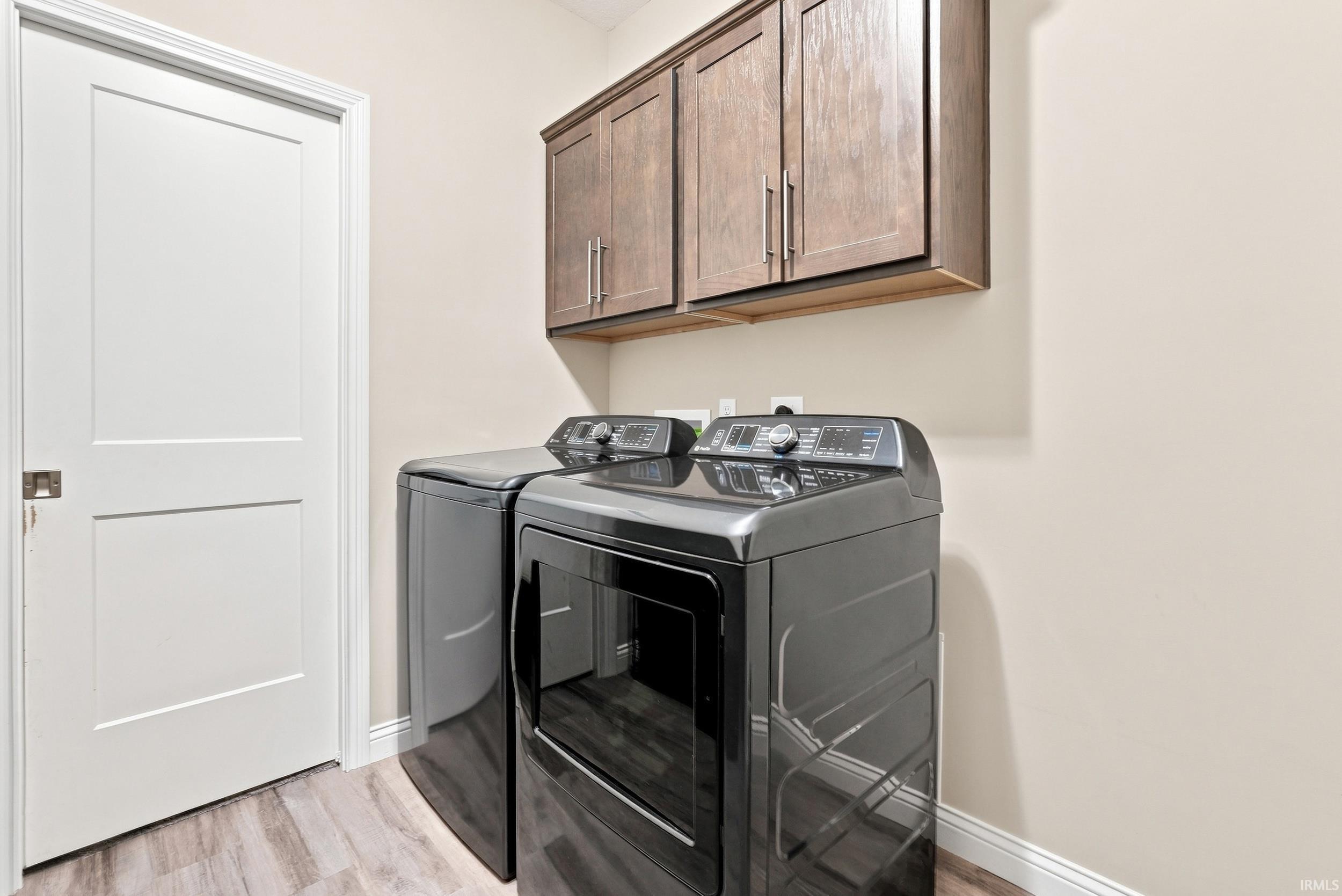 Wood-finish flooring with light-toned walls, featuring a white paneled door and dark wood-finish cabinetry