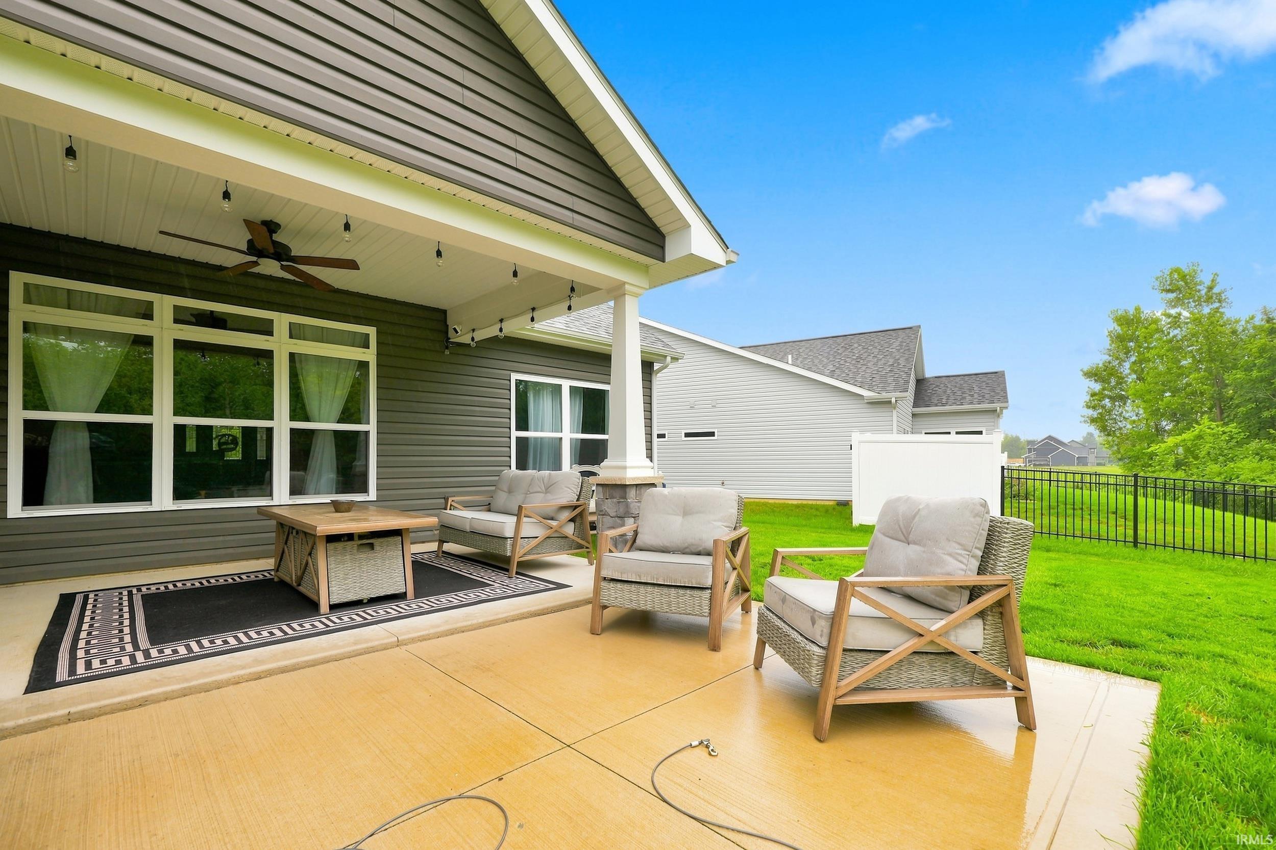 Covered patio with a ceiling fan, string lighting, and direct access to a fenced yard
