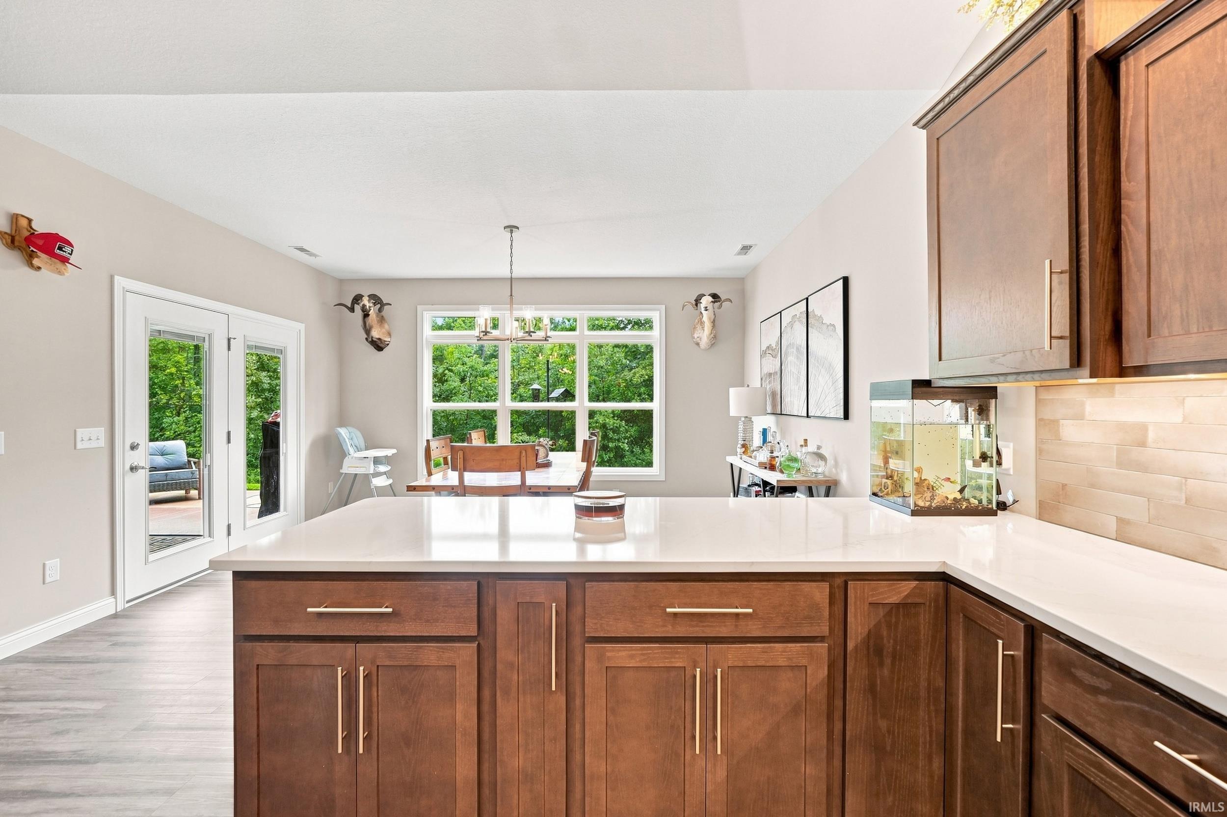 Kitchen island with light-toned countertop, wood cabinetry, and gold-toned hardware
