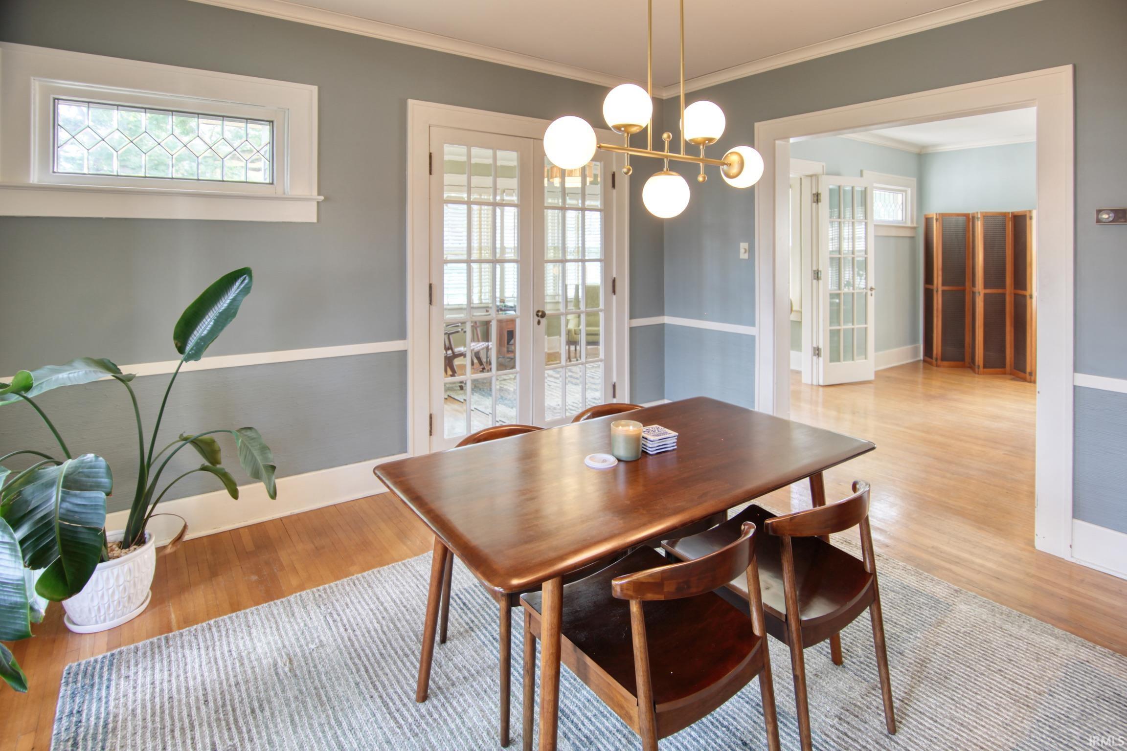 Hardwood flooring, decorative trim, leaded glass transom window, French doors, and a modern chandelier