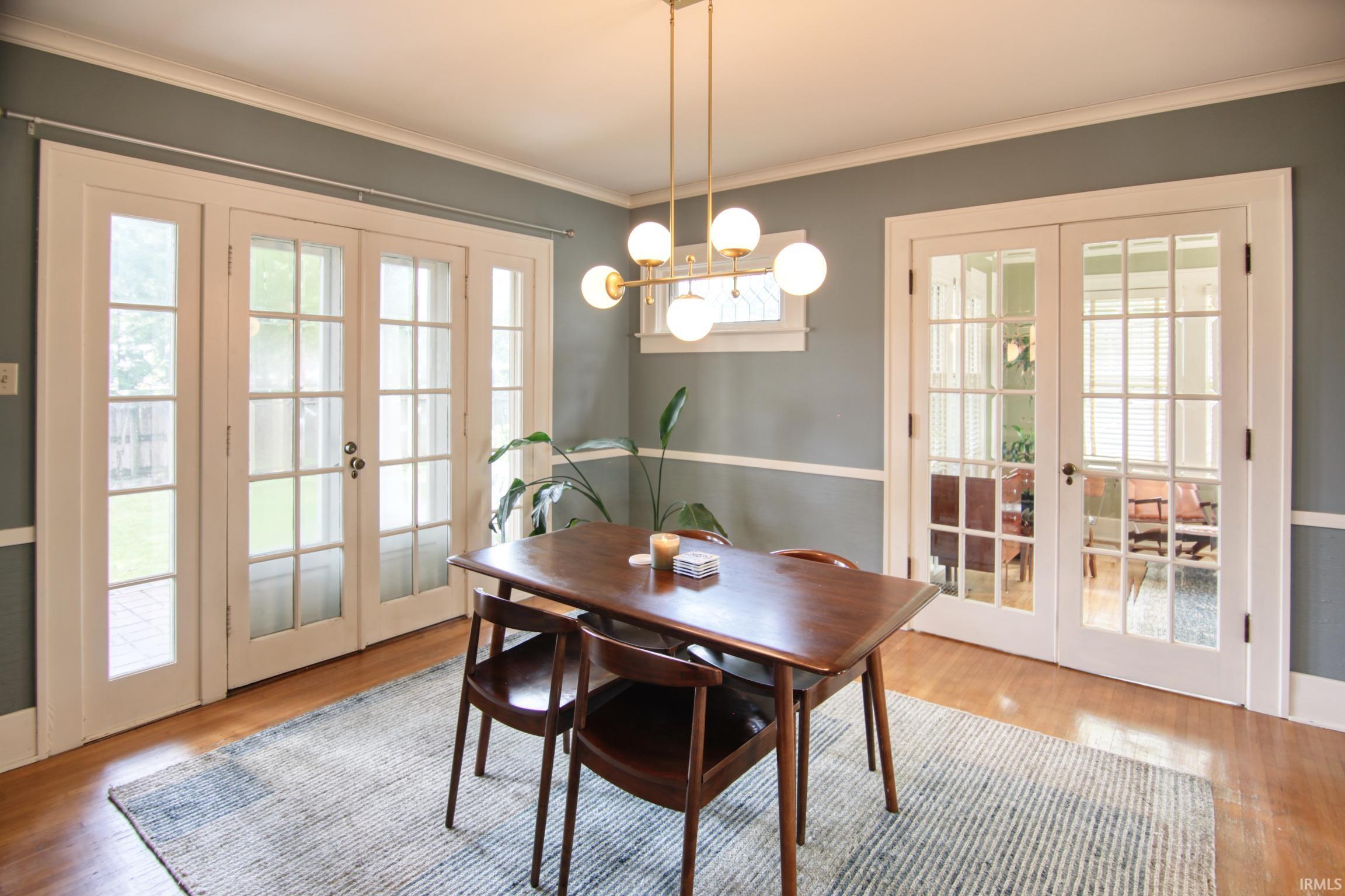 Hardwood flooring throughout, with a contemporary chandelier, and two sets of glass-paned French doors