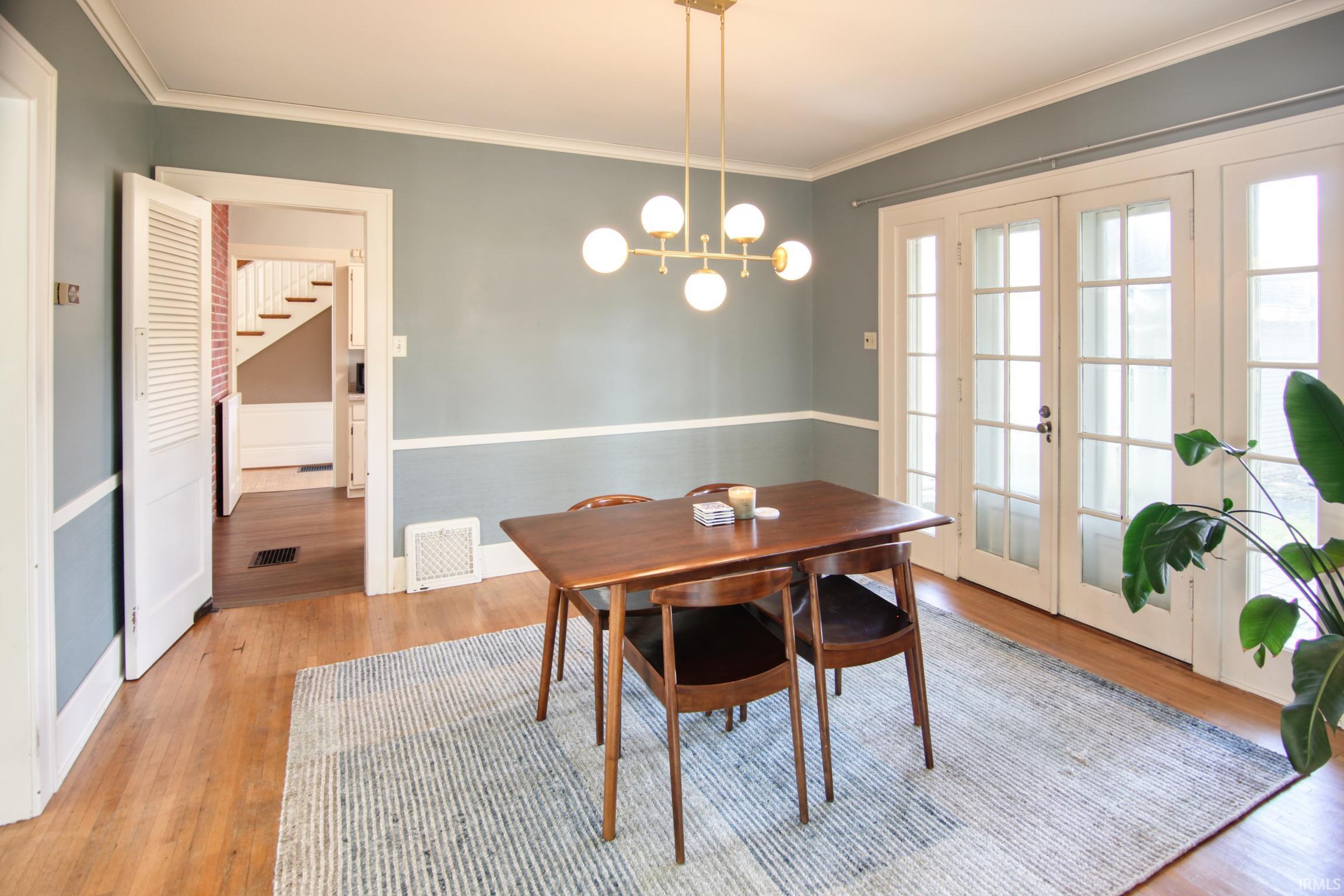 Hardwood flooring, painted walls with chair rail trim, and a modern chandelier