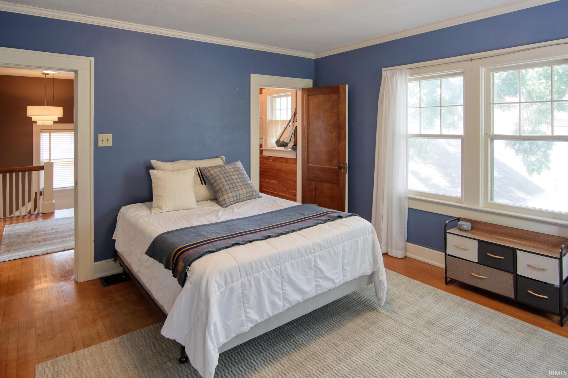 Hardwood flooring, painted walls, crown molding, double windows, and a paneled wood door
