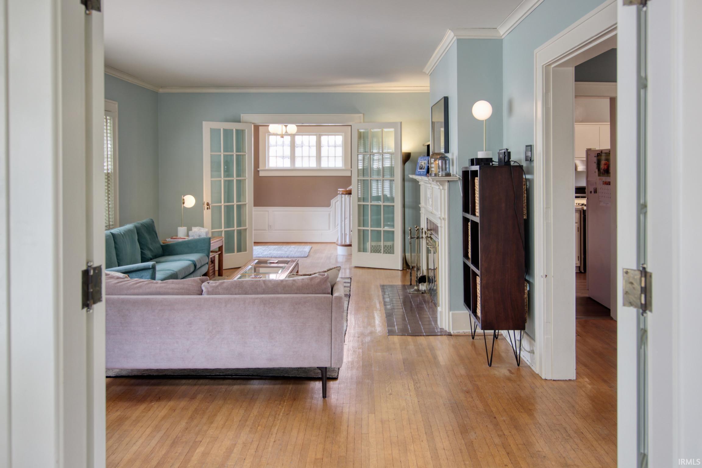 Hardwood flooring, crown molding, double French doors, fireplace, and white trim