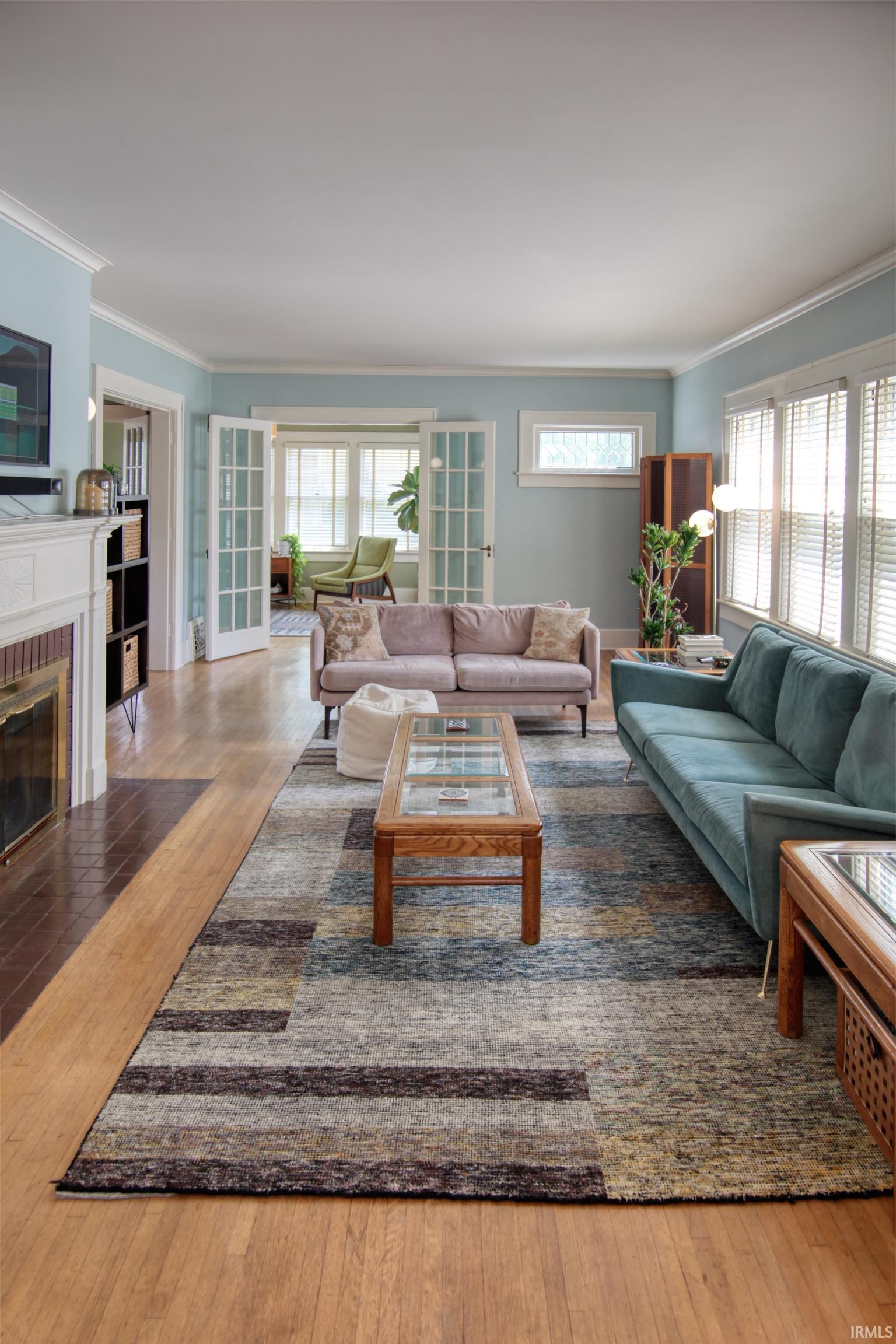 Hardwood flooring, crown molding, and a fireplace with a decorative mantel
