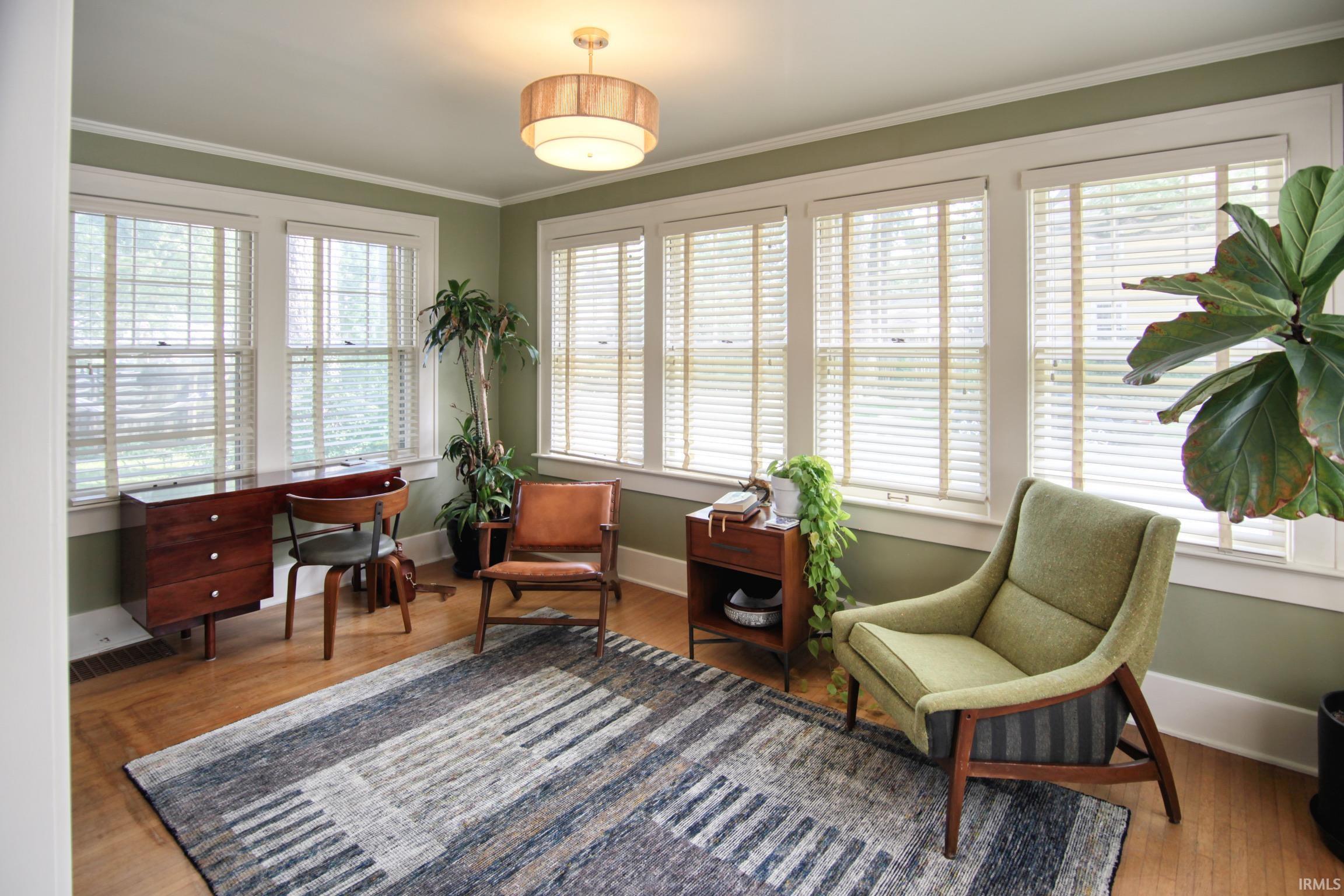 Hardwood flooring, multiple windows with blinds, recessed lighting, crown molding, and wall paneling