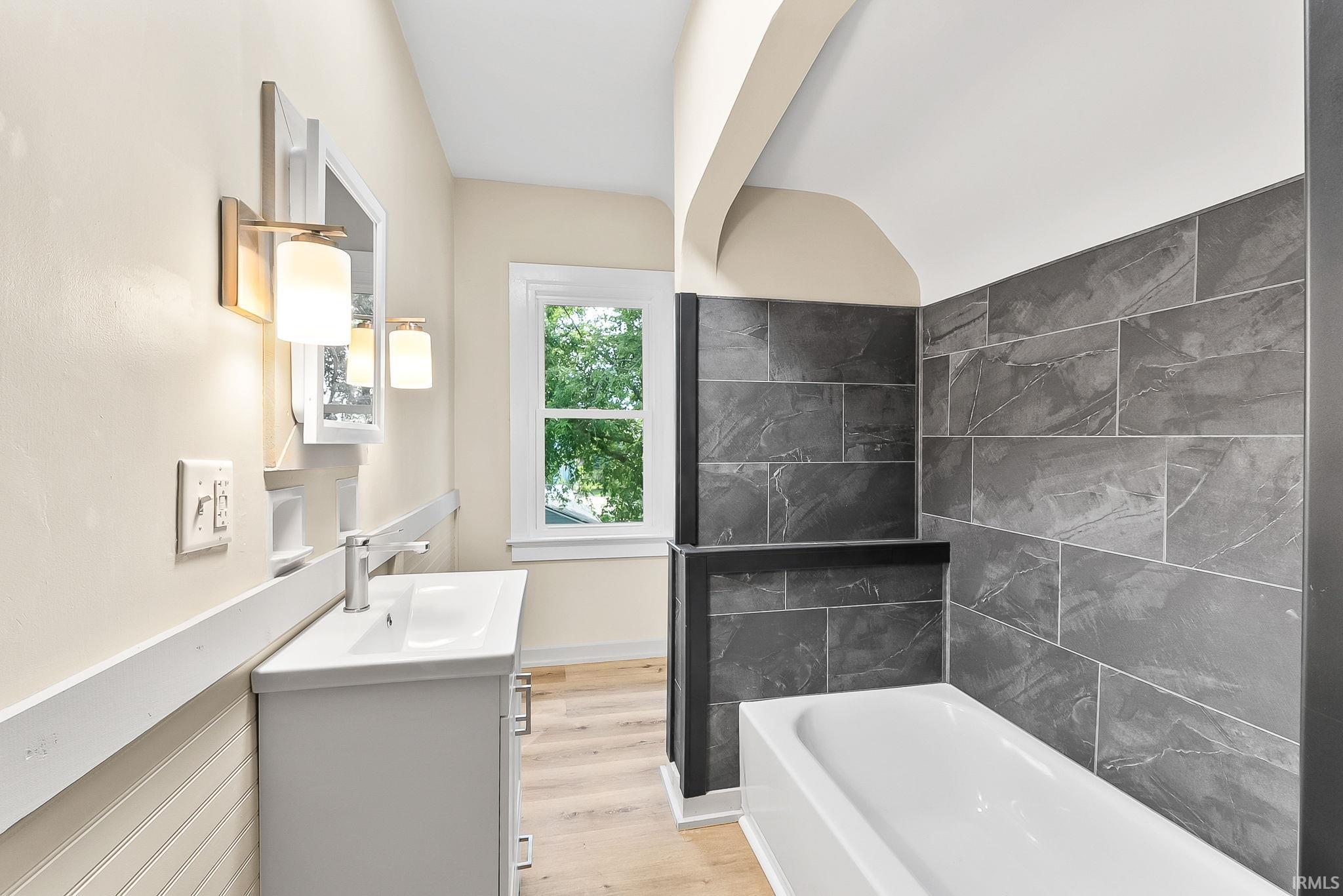 White vanity with a rectangular sink and a chrome faucet, illuminated by two wall-mounted sconces