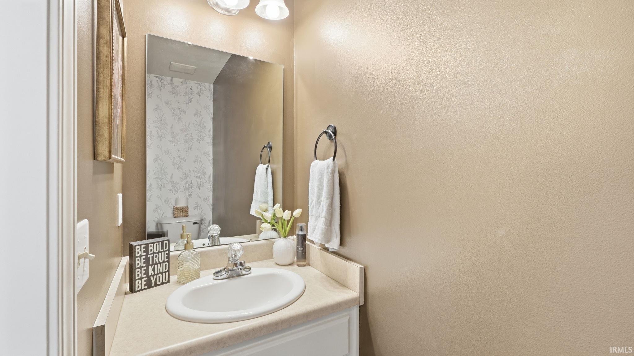 Built-in vanity with an integrated sink, polished chrome faucet, and expansive wall-mounted mirror
