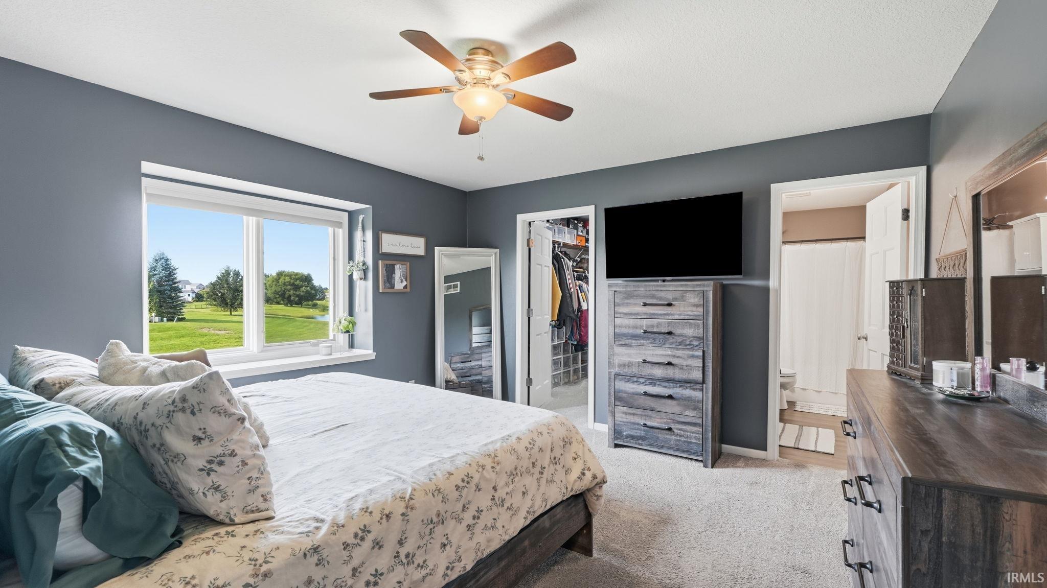 Ceiling fan with integrated lighting, window with white trim, built-in closet with shelving, and carpeted flooring