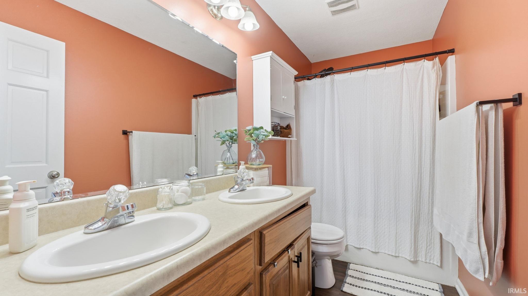 Double vanity with integrated sinks, wood-finish cabinetry, and a full-width mirror
