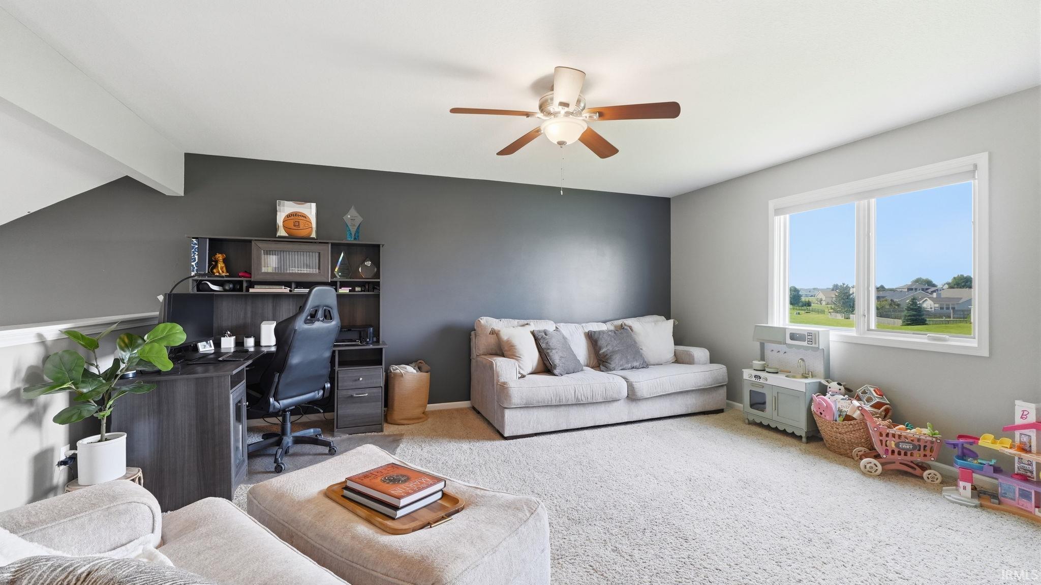Spacious room with a ceiling fan, large window, and built-in desk and shelving unit