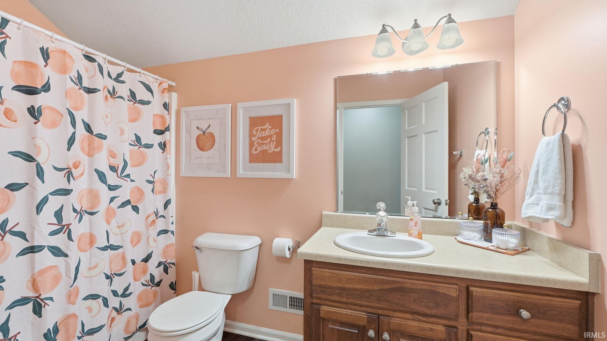 Bathroom featuring a wood-finish vanity with a built-in sink, a wall-mounted mirror, and a three-light vanity fixture
