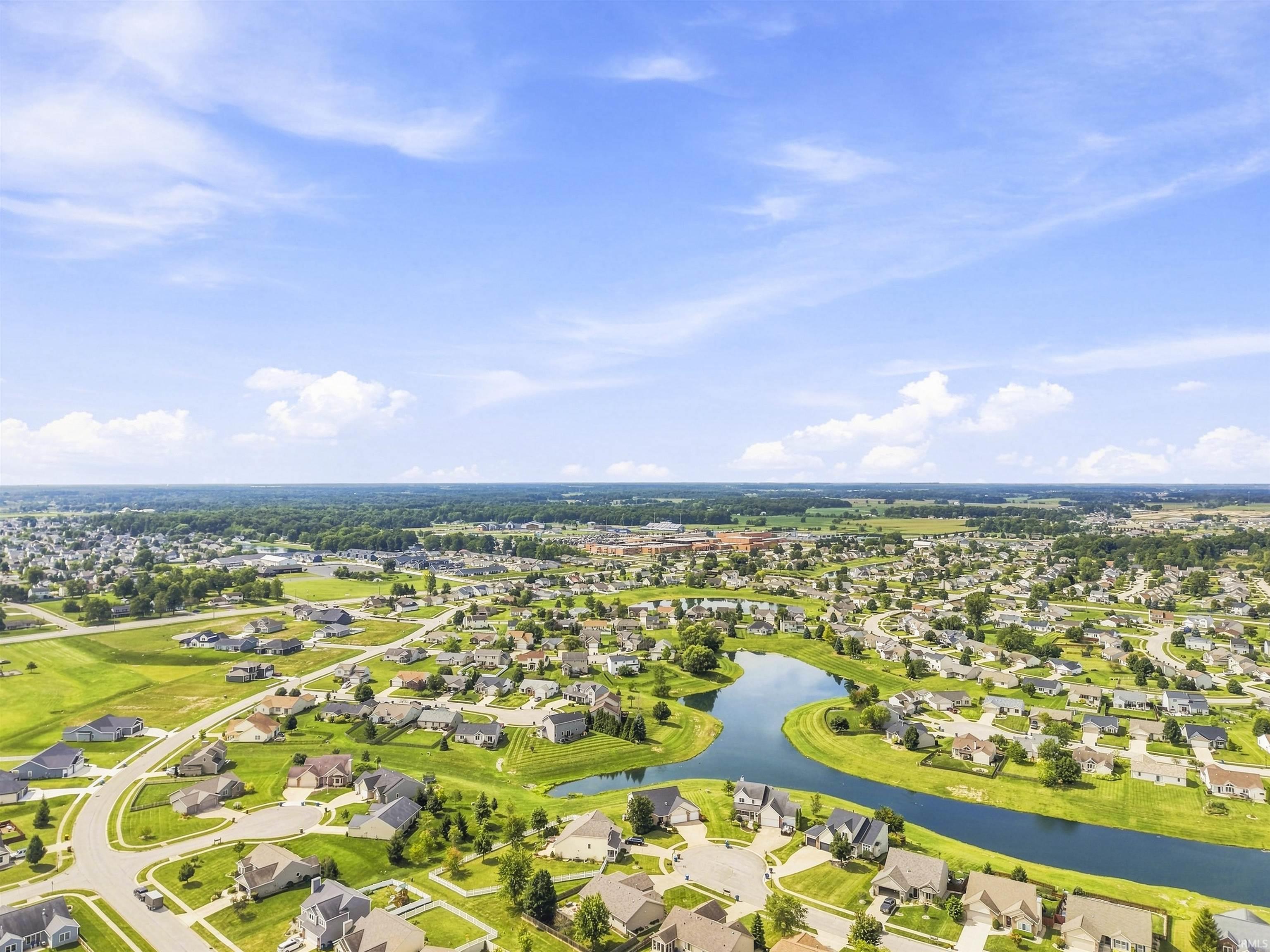 Expansive residential area featuring numerous homes, a winding waterway, and extensive green spaces