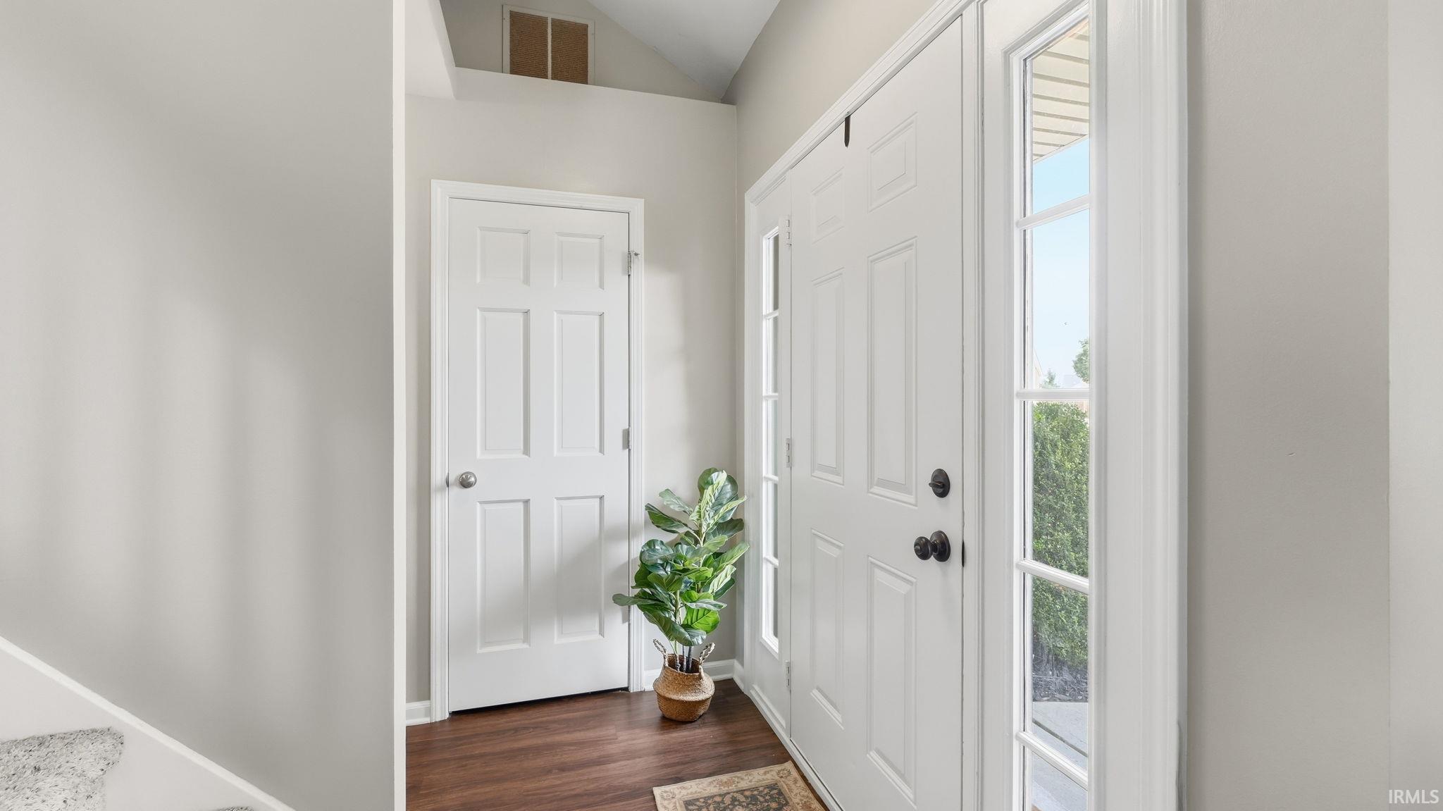 Entryway featuring a paneled door with side windows, wood-finish flooring, and white interior doors