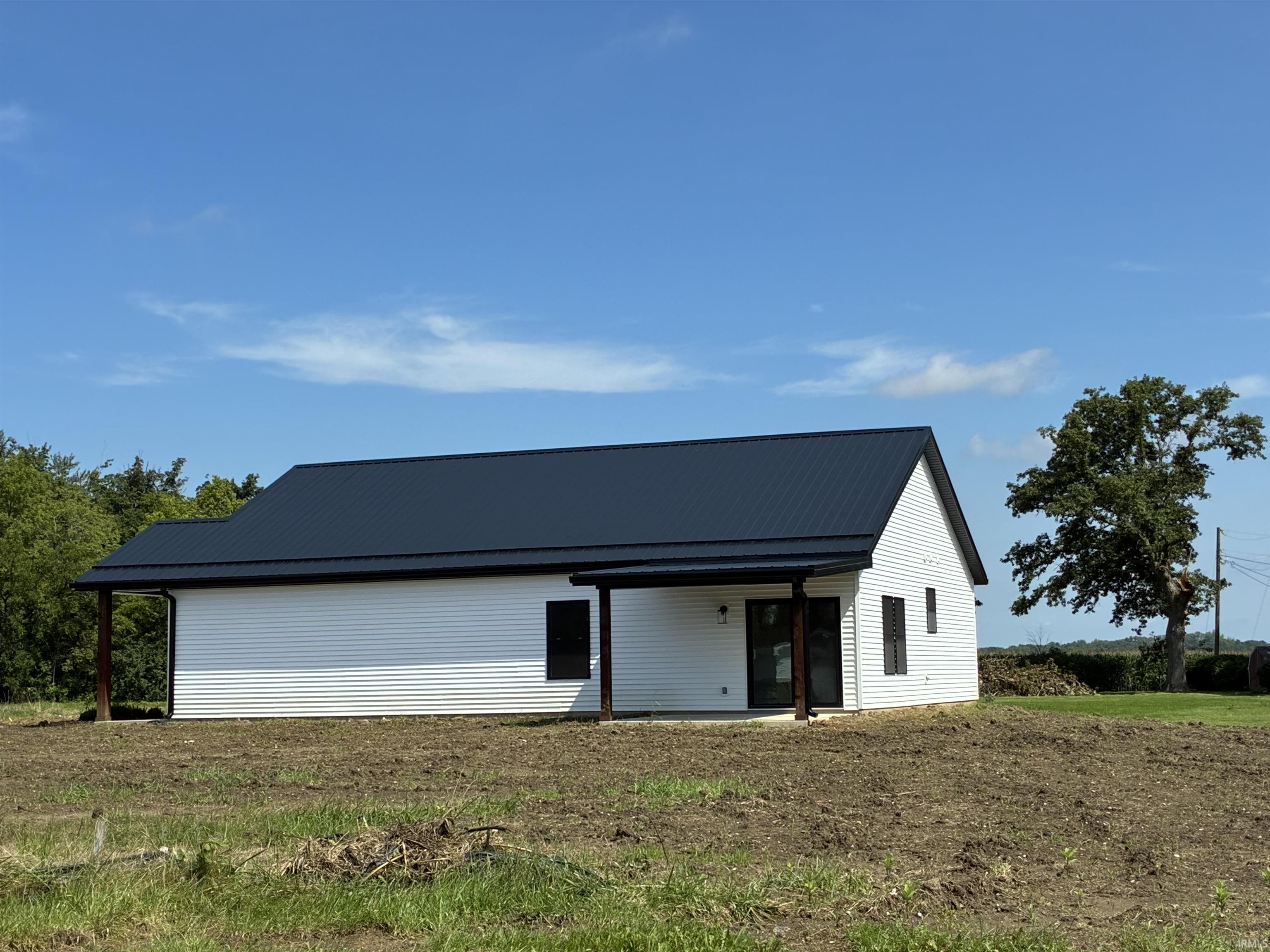 White siding exterior with a dark metal roof, featuring covered porch spaces, and dark-framed windows