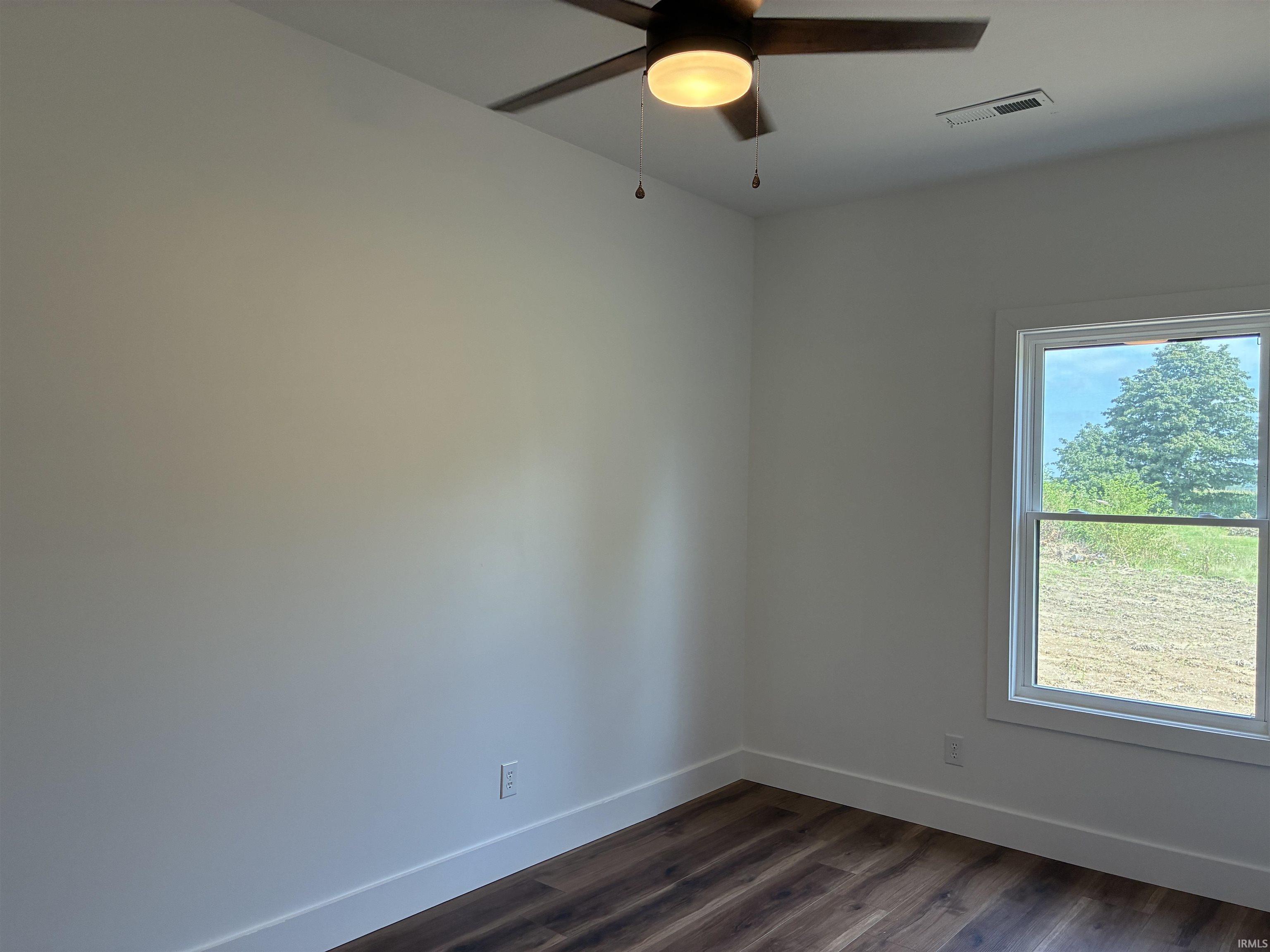 Wood-finish flooring, white trim, and a ceiling fan with integrated lighting