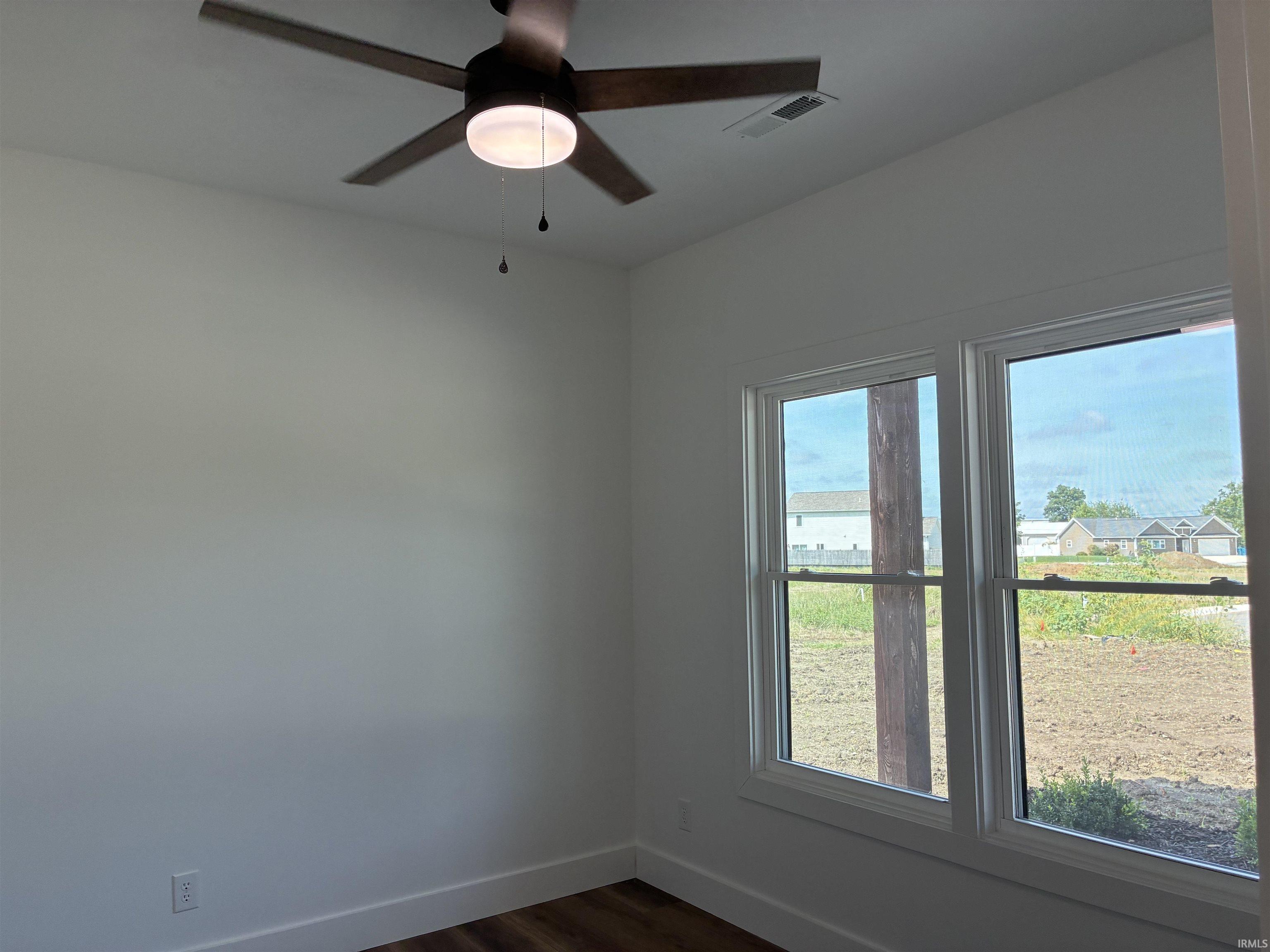 Wood-finish flooring, white trim, and two large windows