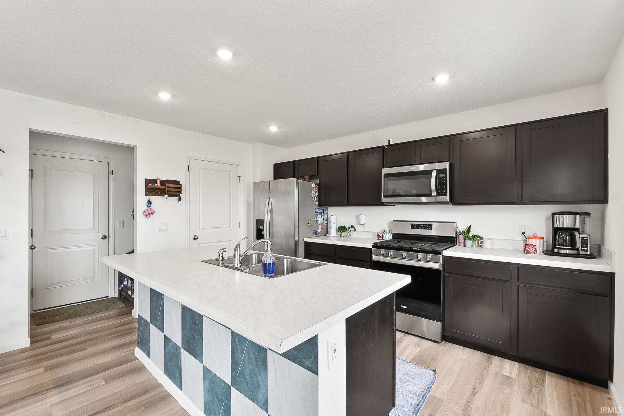 Kitchen featuring dark wood-finish cabinetry, white countertops, a stainless steel gas range, and a stainless steel built-in microwave