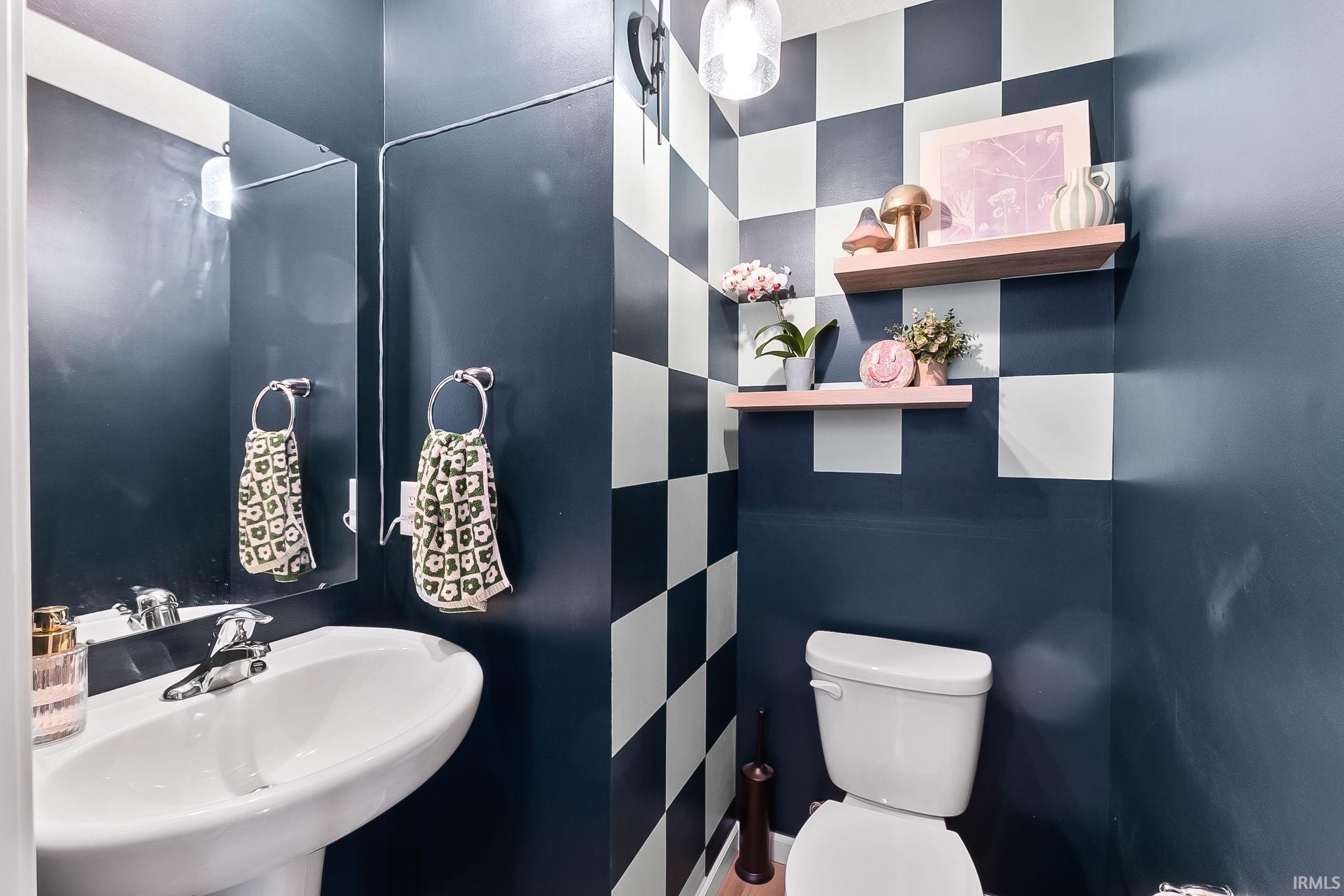 Pedestal sink with chrome faucet, large wall mirror, and checkered wall accent