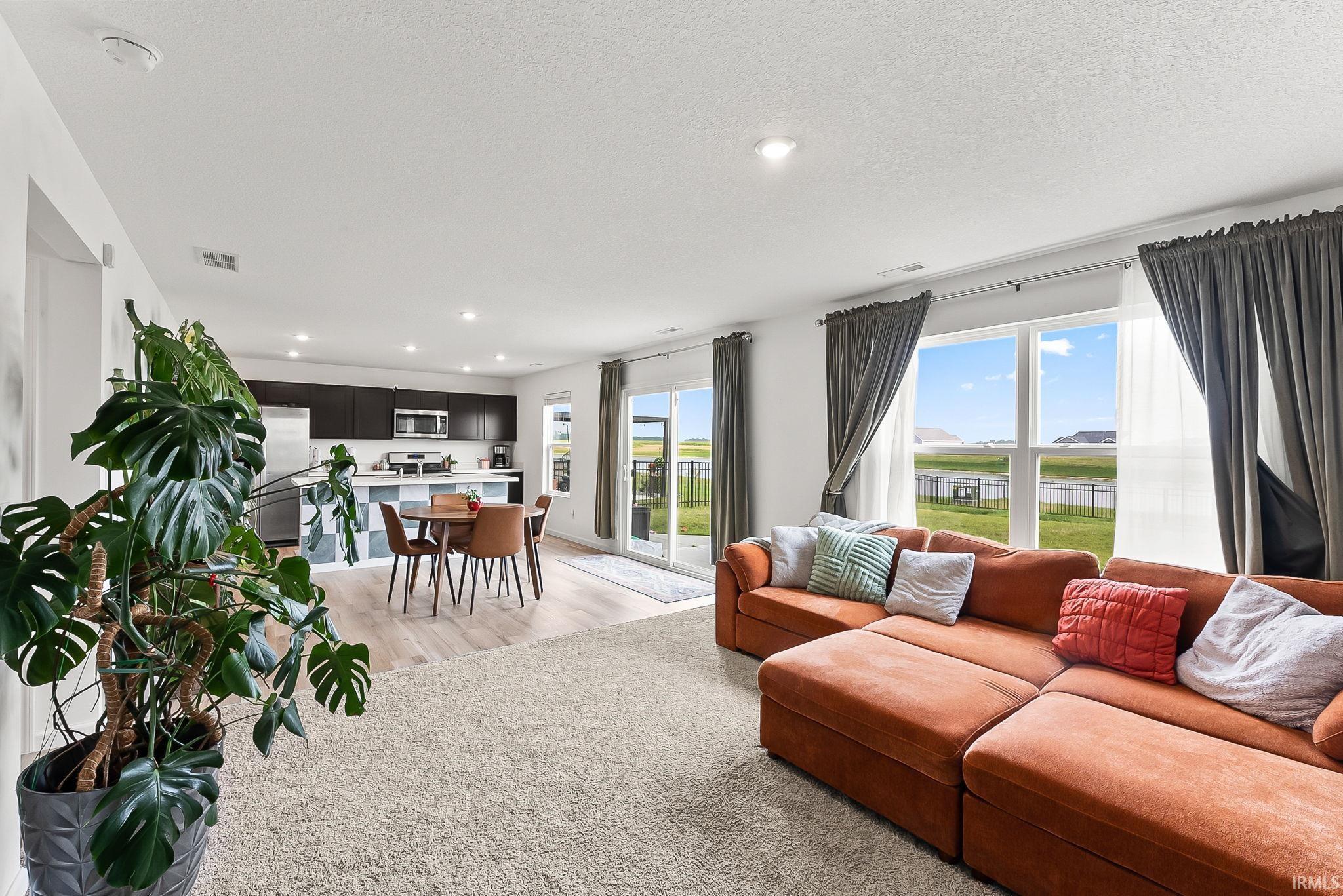 Open-concept interior featuring recessed lighting, light wood-finish flooring, and large windows with outdoor views