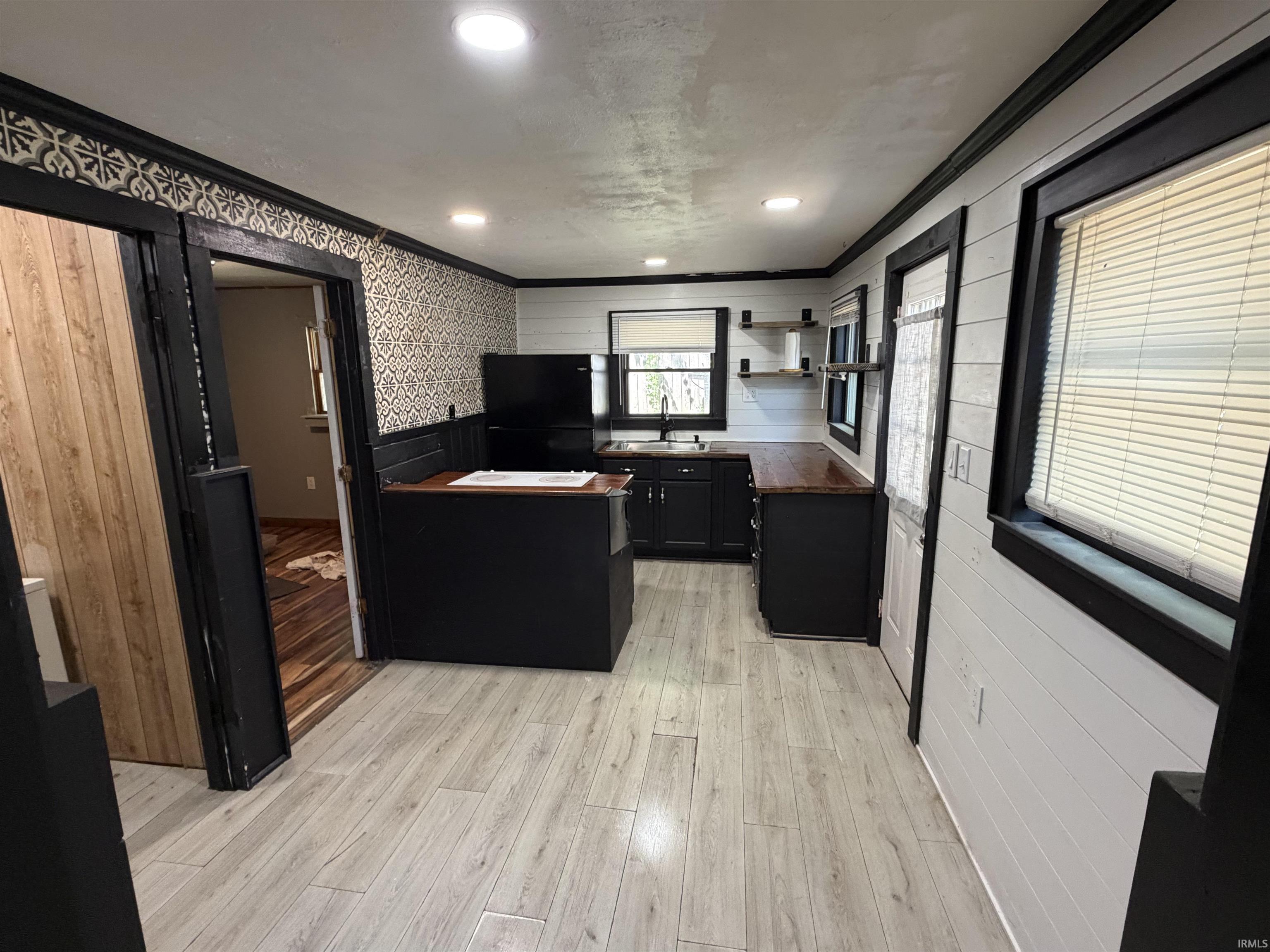 Kitchen featuring light wood-finish flooring, dark cabinetry, and wood countertops