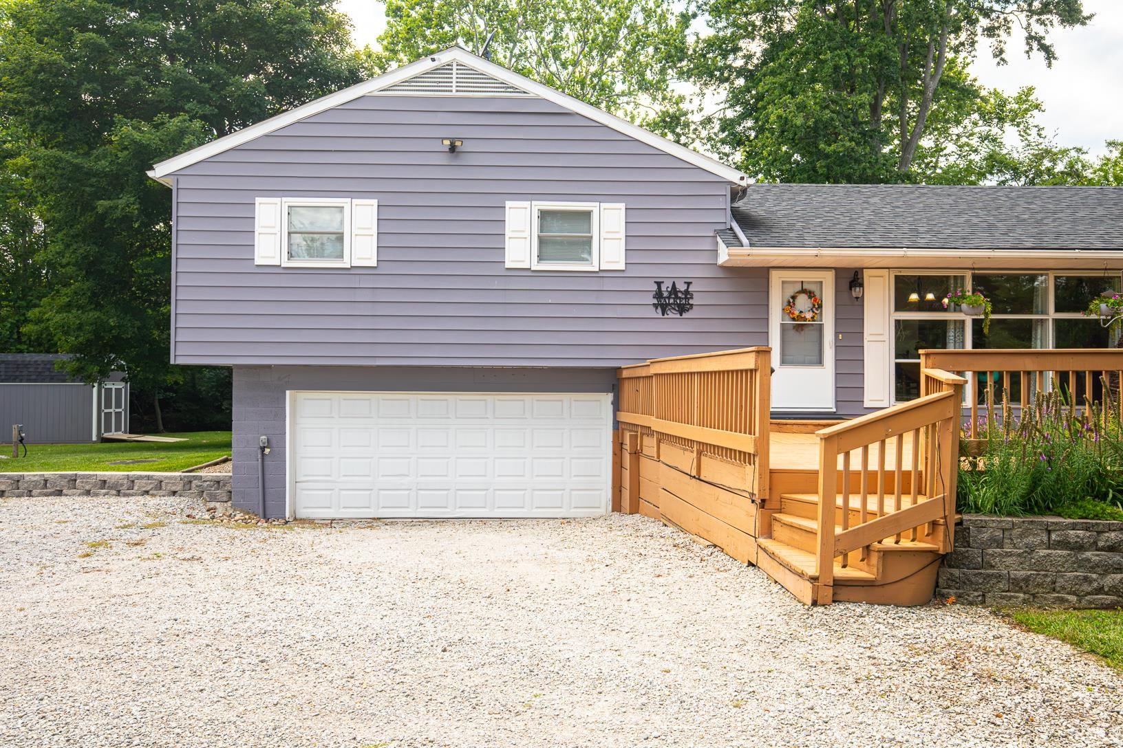 Split-level residence featuring gray siding and white window shutters