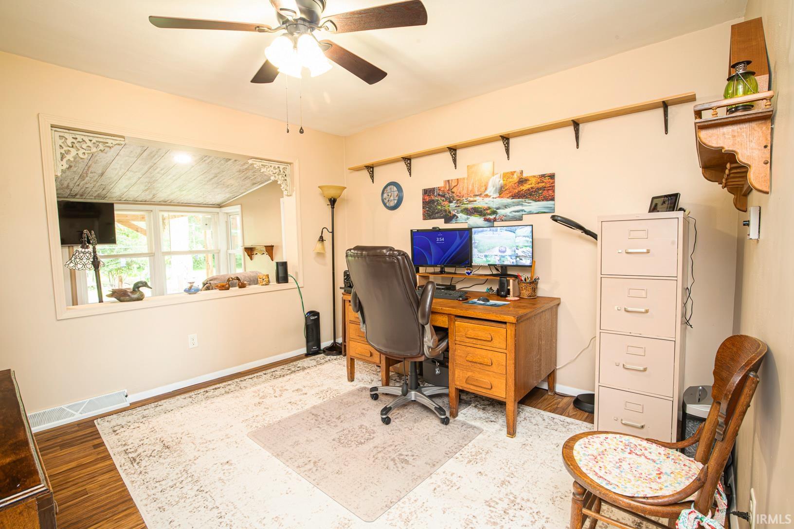 Room featuring wood-finish flooring and a ceiling fan with integrated lighting