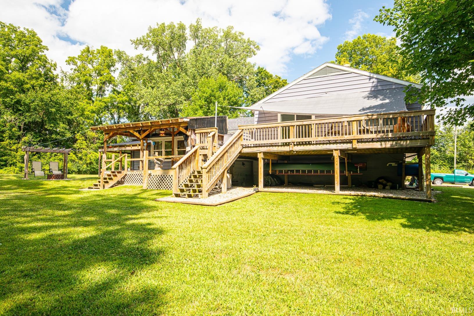 Rear elevation featuring a multi-level wood deck, covered patio, and ground-level storage area