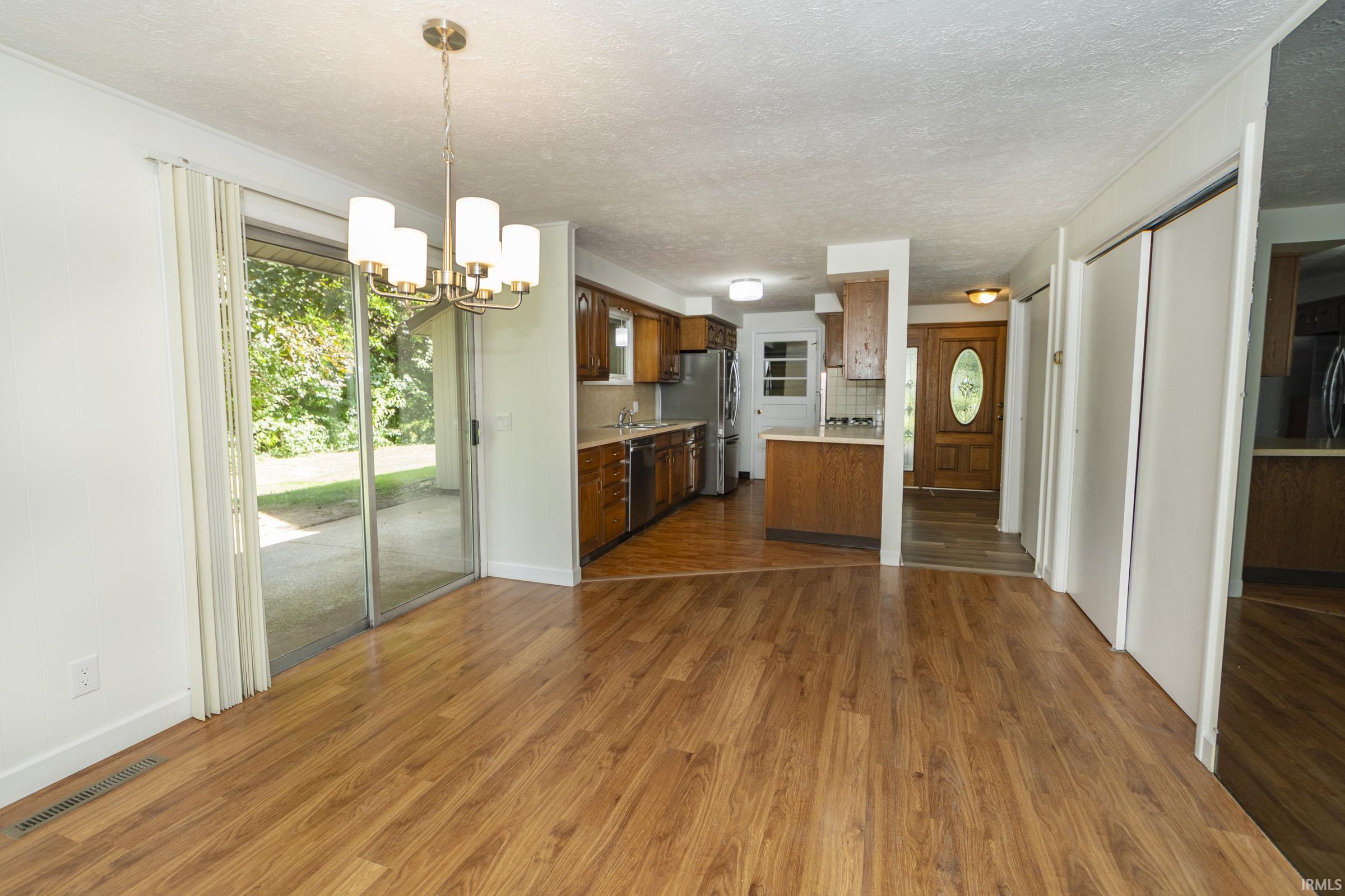 Open-concept living and dining area with hardwood flooring, pendant lighting, and sliding glass doors to the exterior
