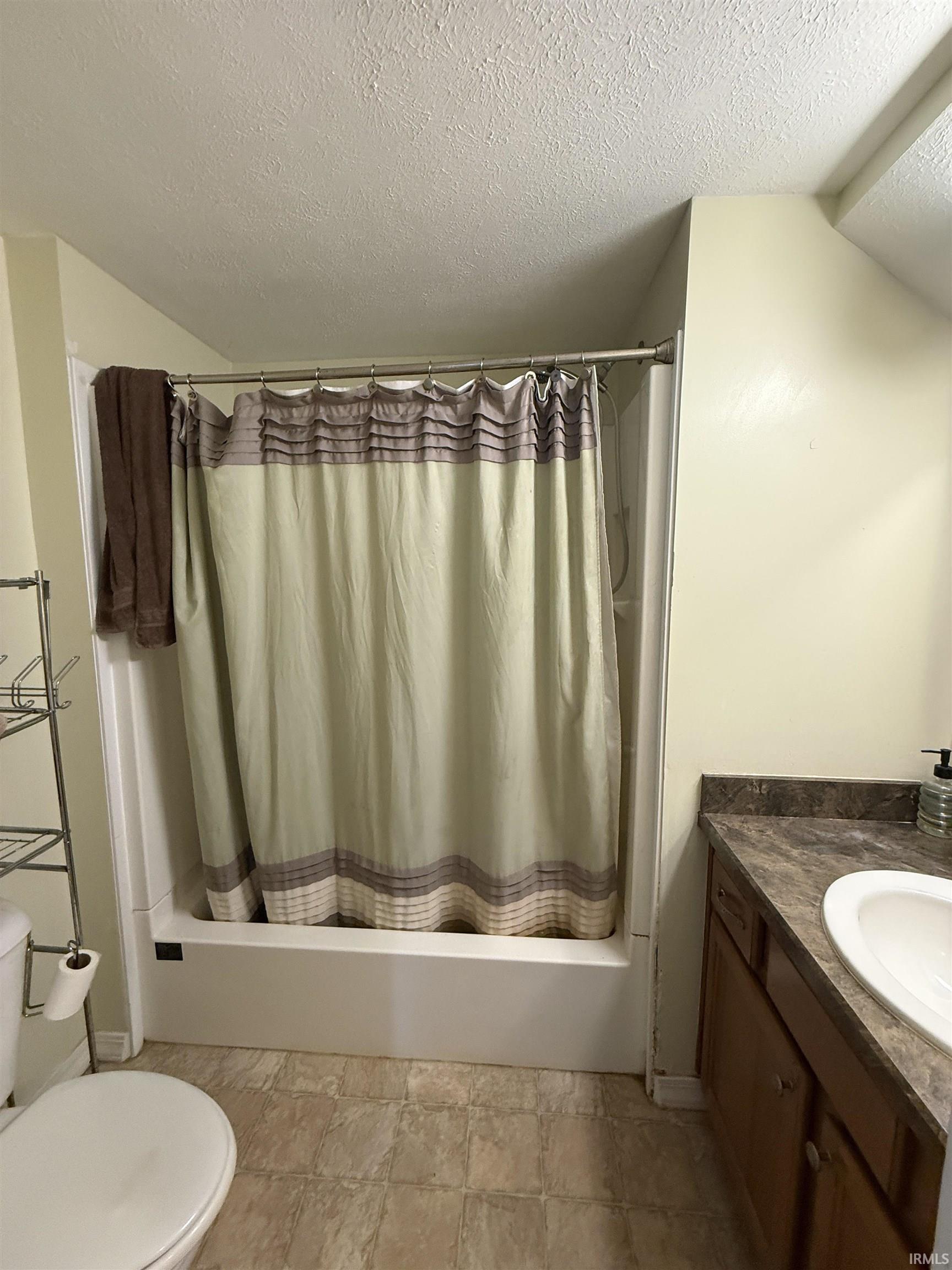 Bathtub shower combination with a single basin vanity and wood-finish cabinetry