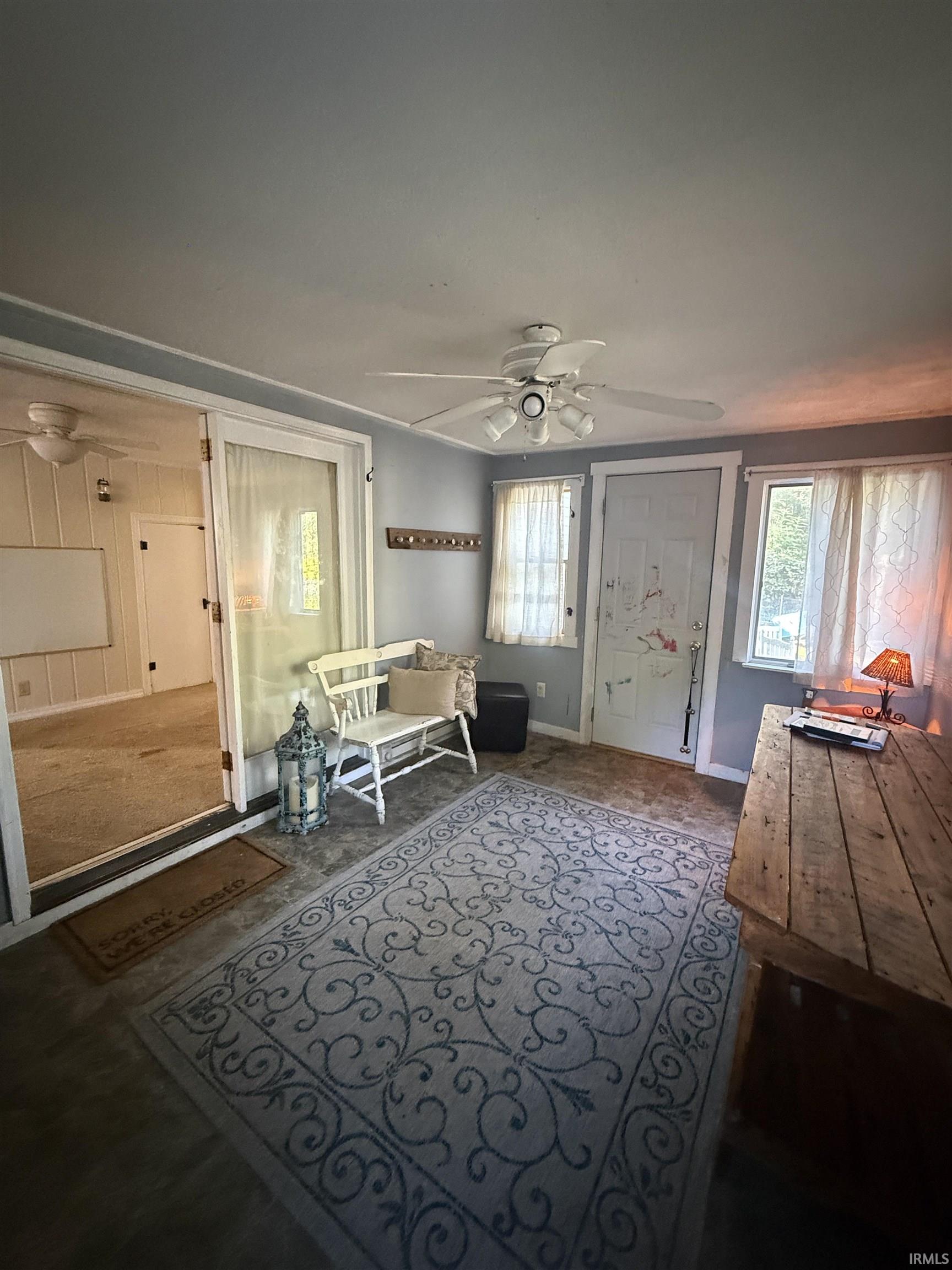 Light gray wall paint, multiple windows, ceiling fan, wood-finish flooring, and a built-in coat rack