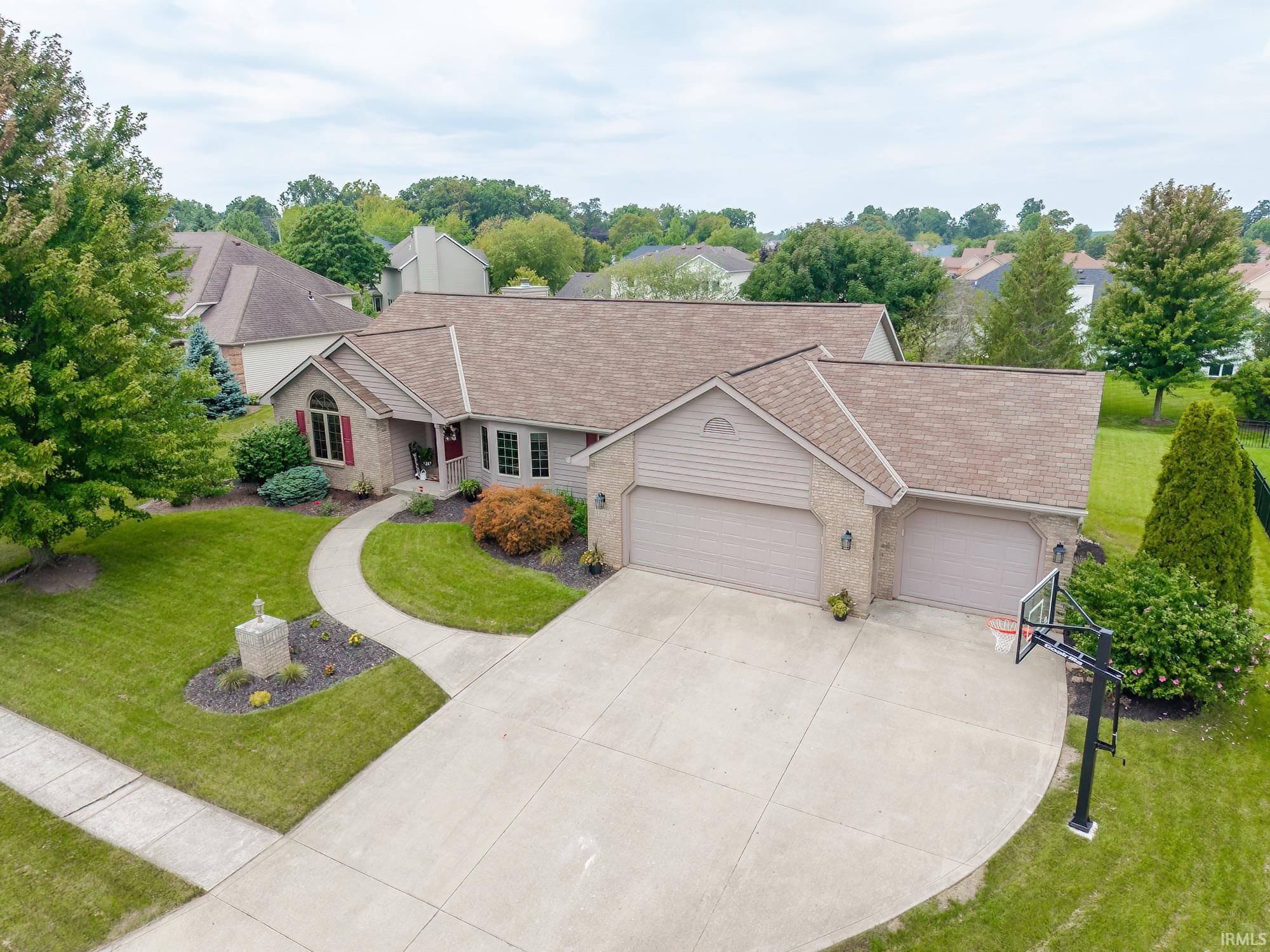Single-story residence featuring a brick and siding exterior, multi-car attached garage, curved concrete driveway, and a well-maintained front yard with mature landscaping
