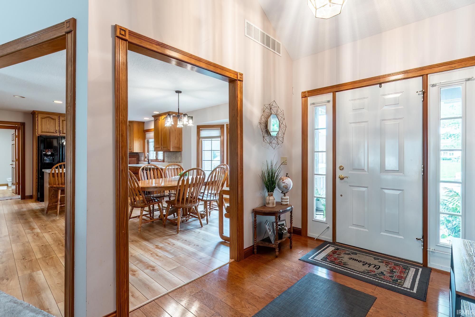 Entryway featuring wood-finish flooring, a paneled entry door with sidelights, and a decorative ceiling light fixture