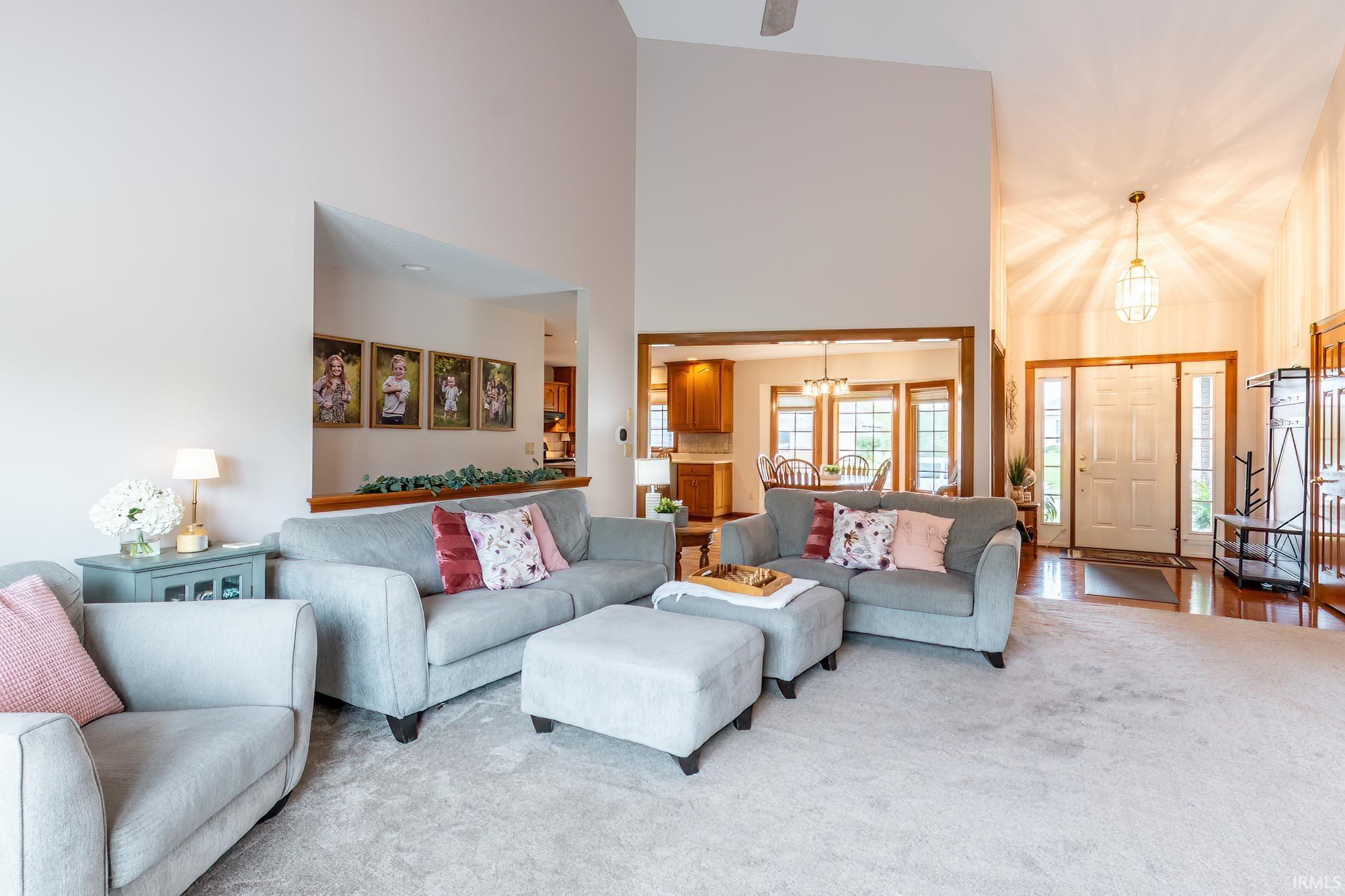 Vaulted ceiling, recessed lighting, carpet flooring, wood-finish flooring, and a decorative pendant light fixture