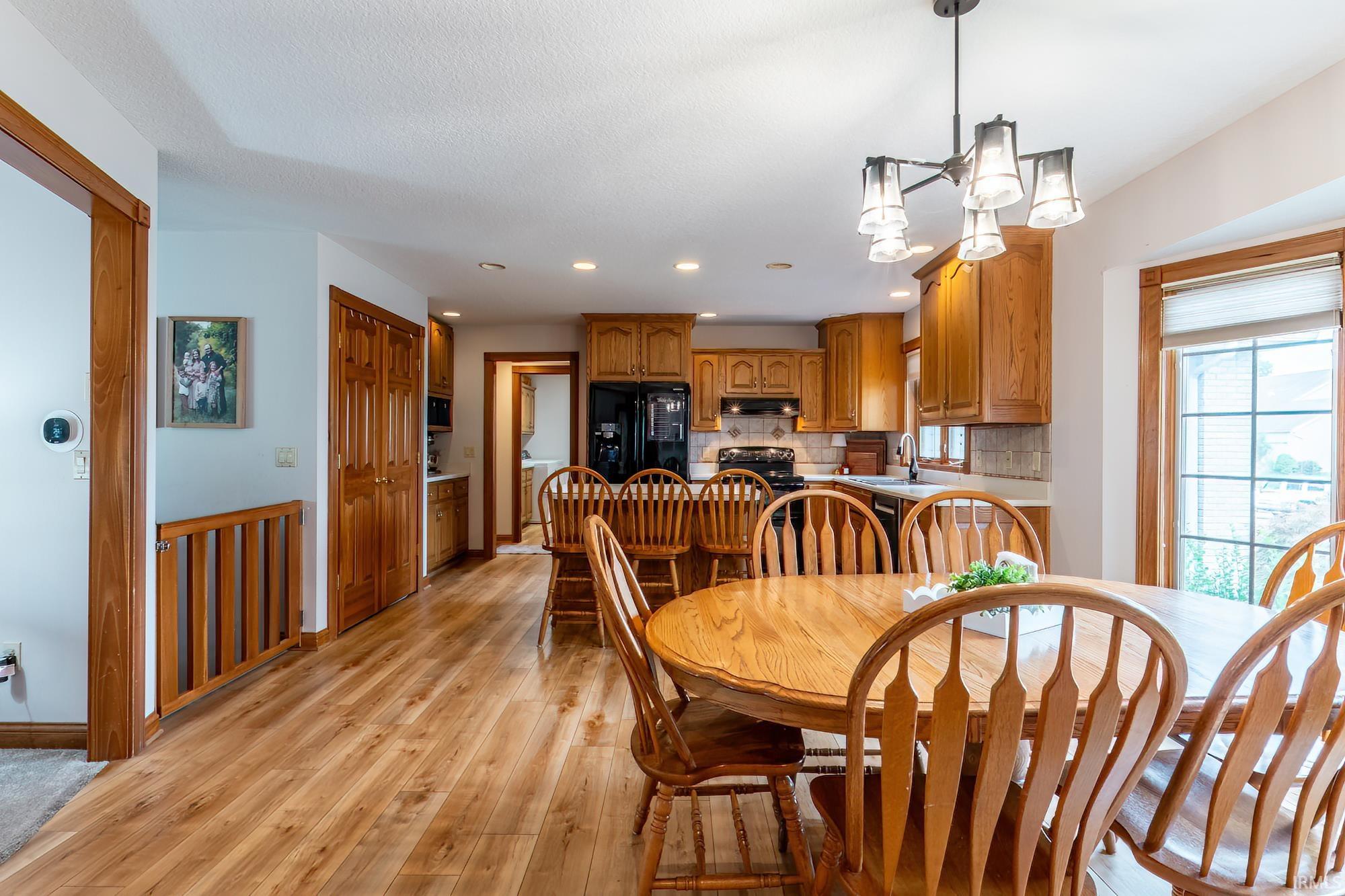 Wood-finish flooring throughout, with a recessed kitchen, wood cabinetry, and a black appliance suite