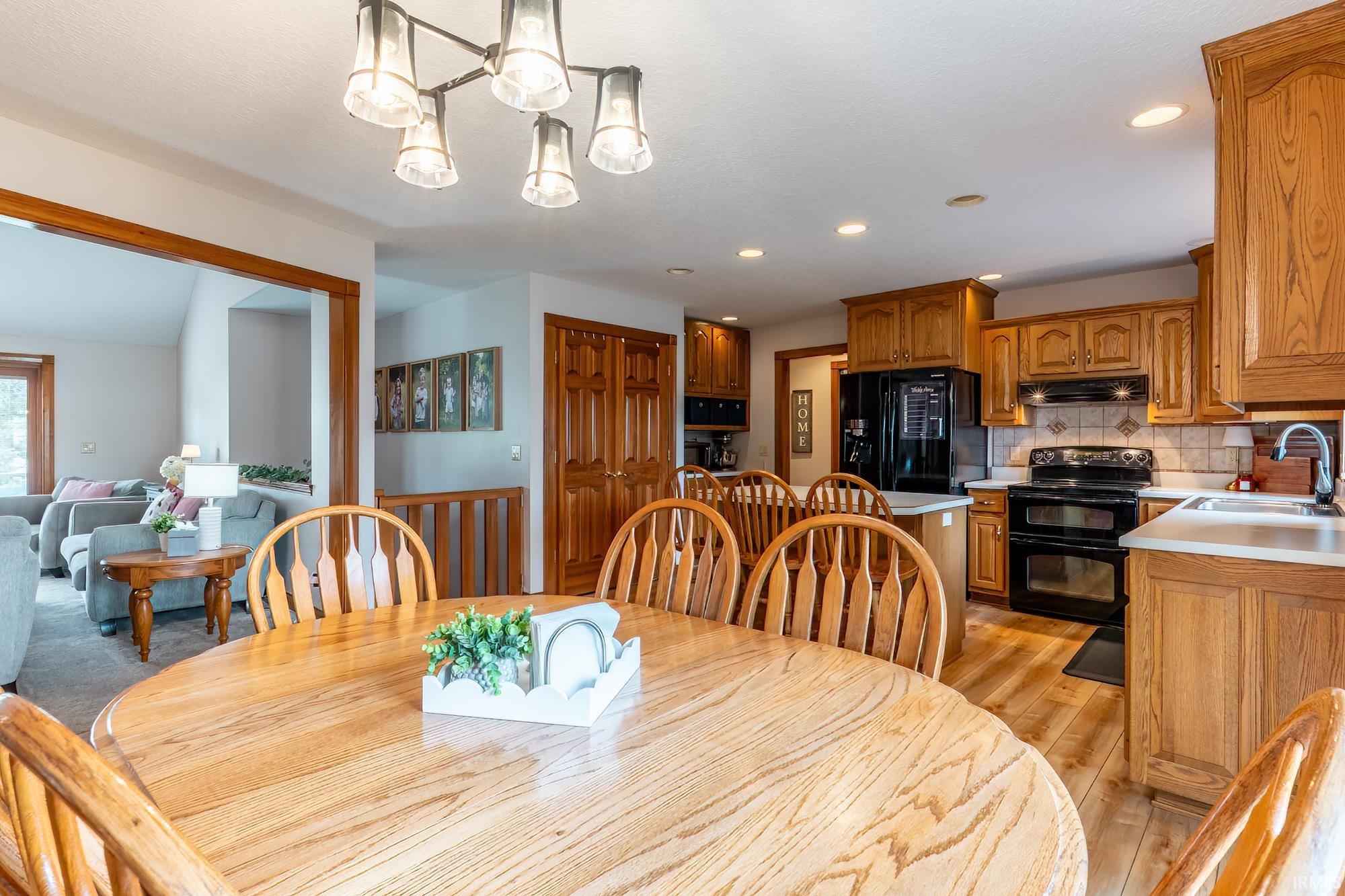Kitchen featuring wood-finish cabinetry, black appliances, light countertops, and tile backsplash