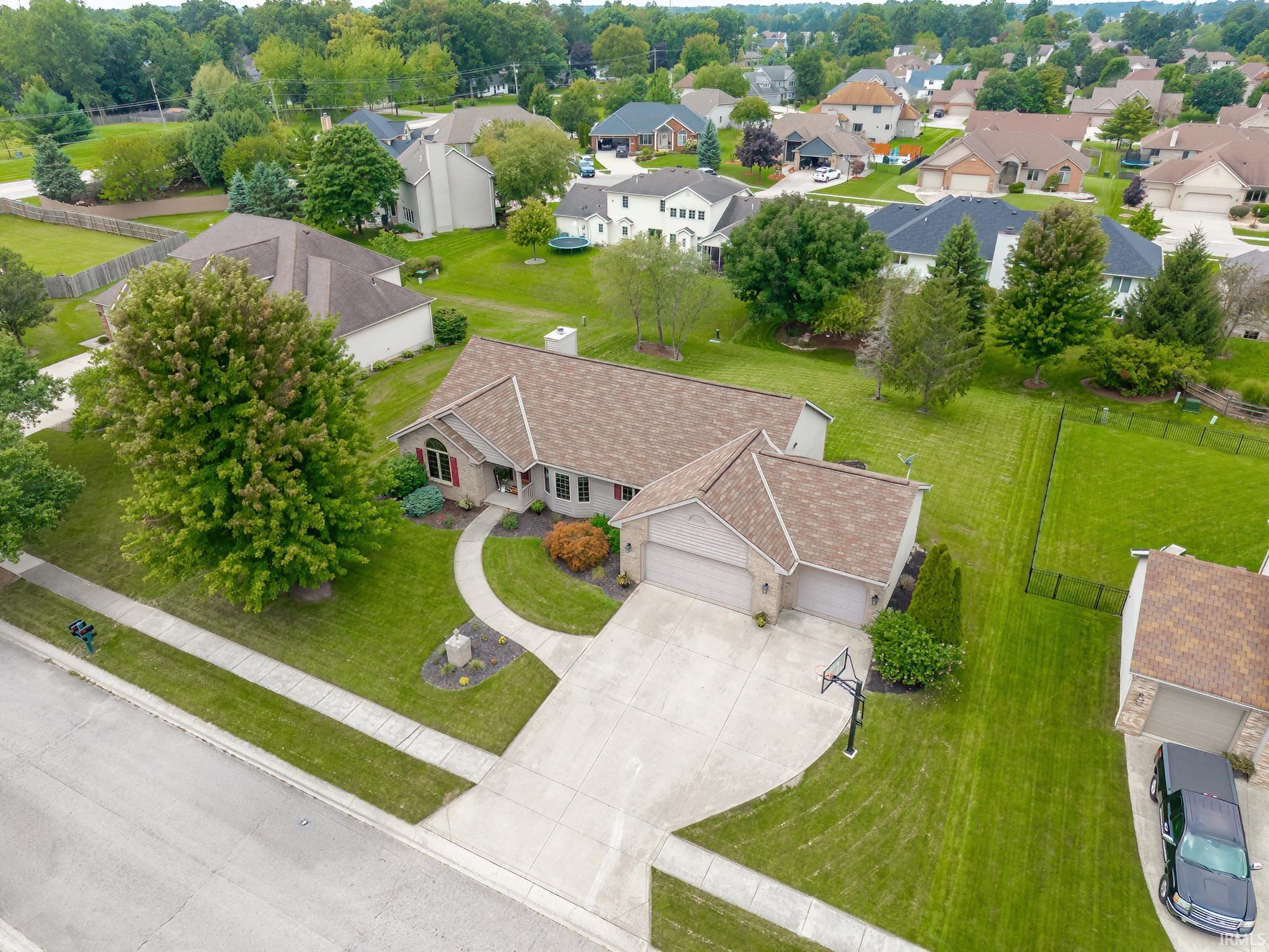 Brick exterior with a gabled roof, attached two-car garage, concrete driveway, and manicured landscaping