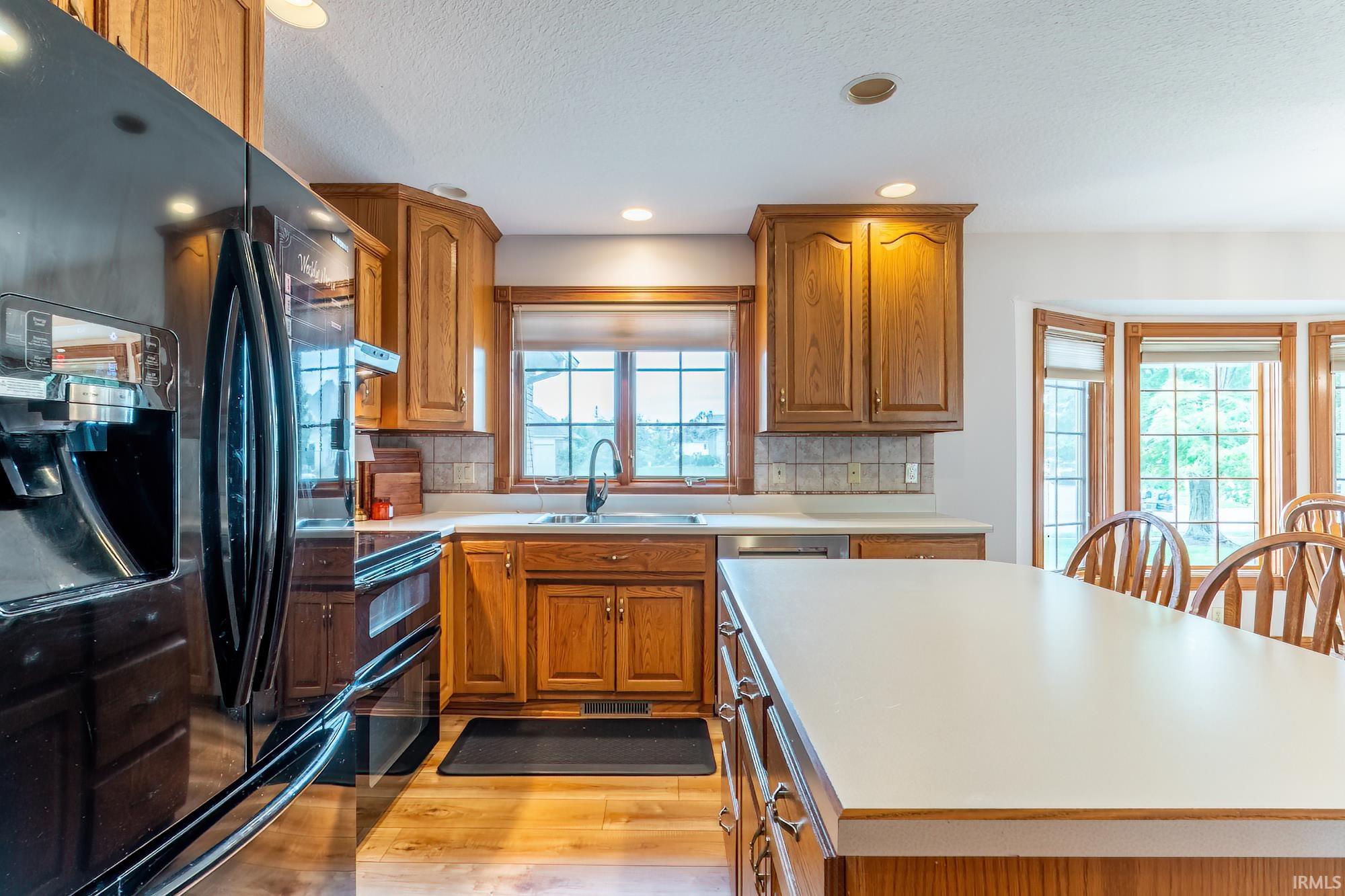 Kitchen featuring wood-finish cabinetry, a large center island, and a bay window