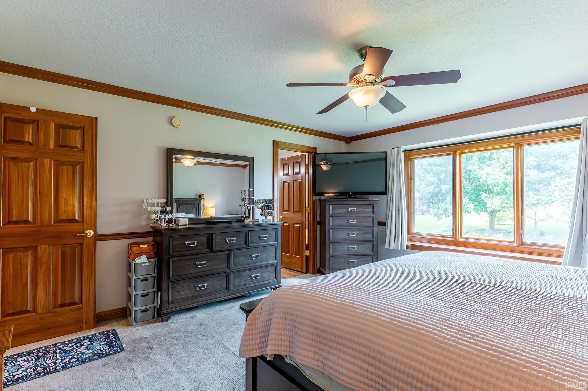 Spacious room featuring wood-finish paneled doors, ceiling fan with integrated lighting, and expansive windows
