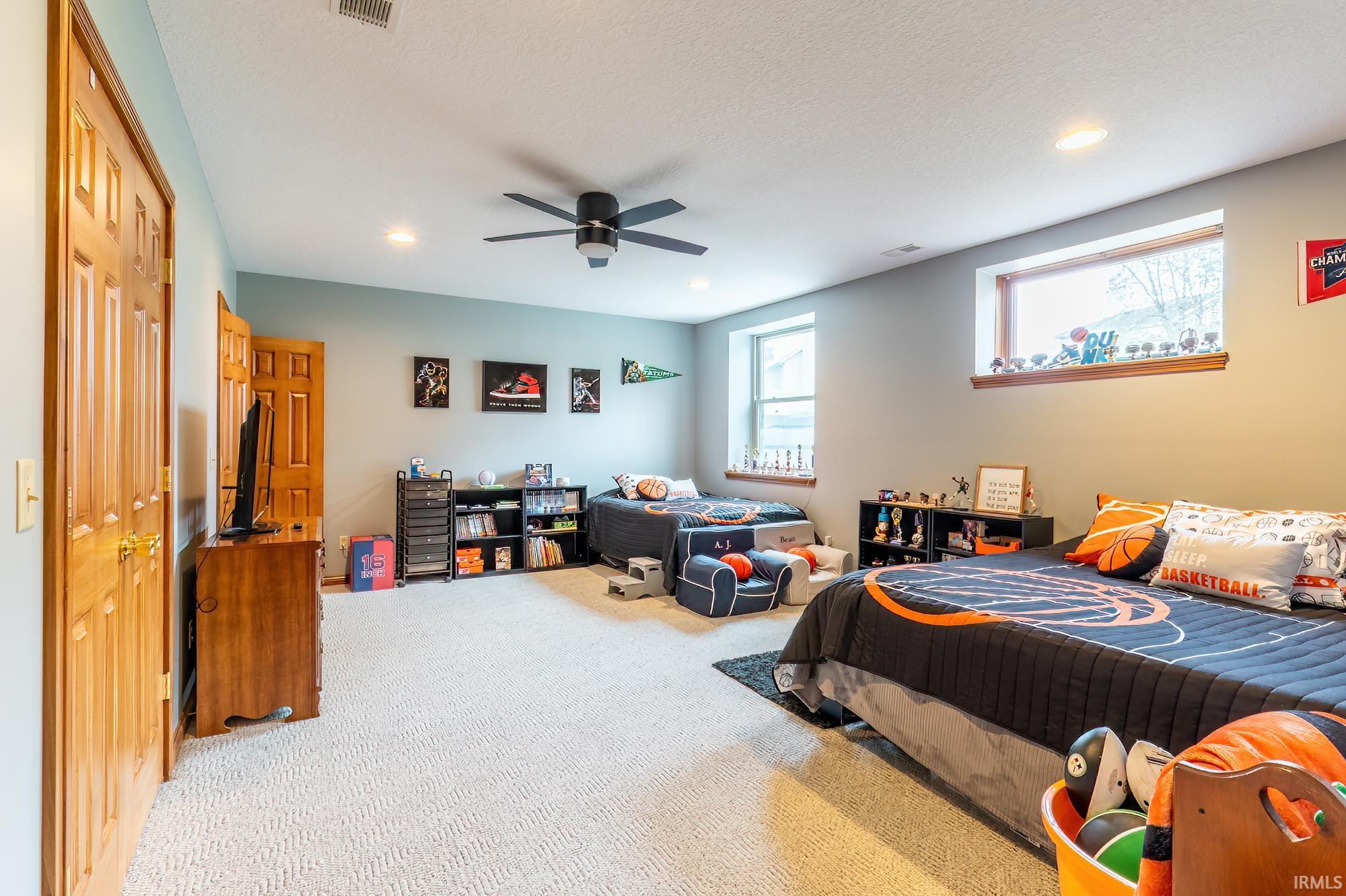 Recessed lighting, light-colored carpeting, two windows, wood-finish doors, and a ceiling fan