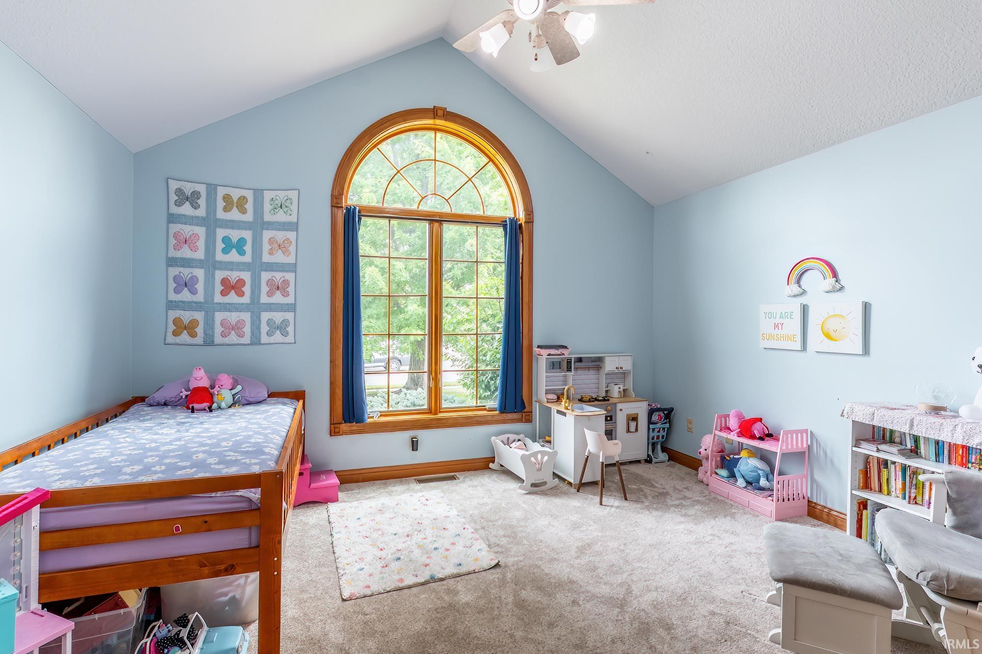 Arched window with wood trim, vaulted ceiling, and ceiling fan
