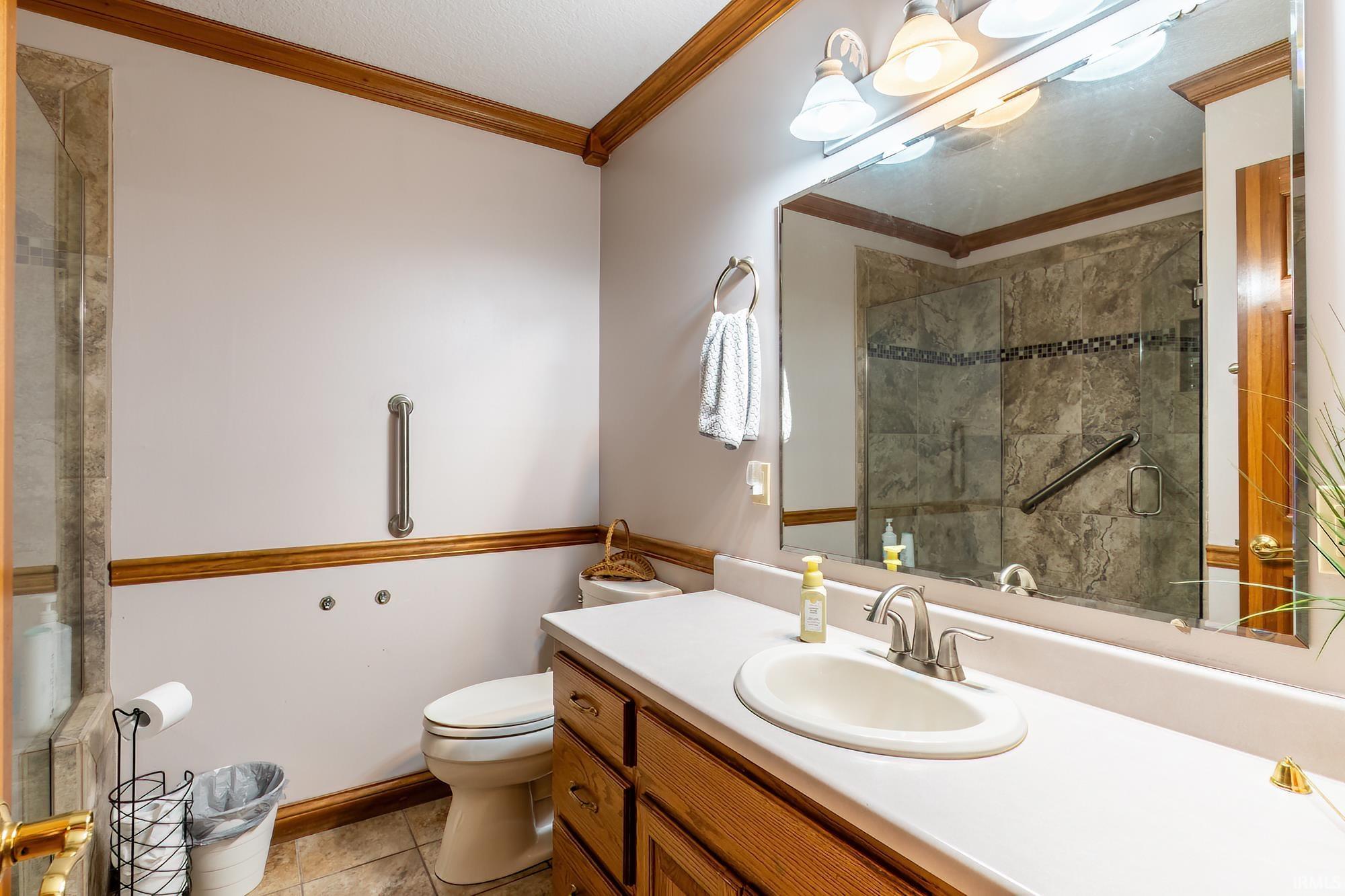 Wood-finish cabinetry with a light-toned countertop, oval undermount sink, and brushed nickel faucet