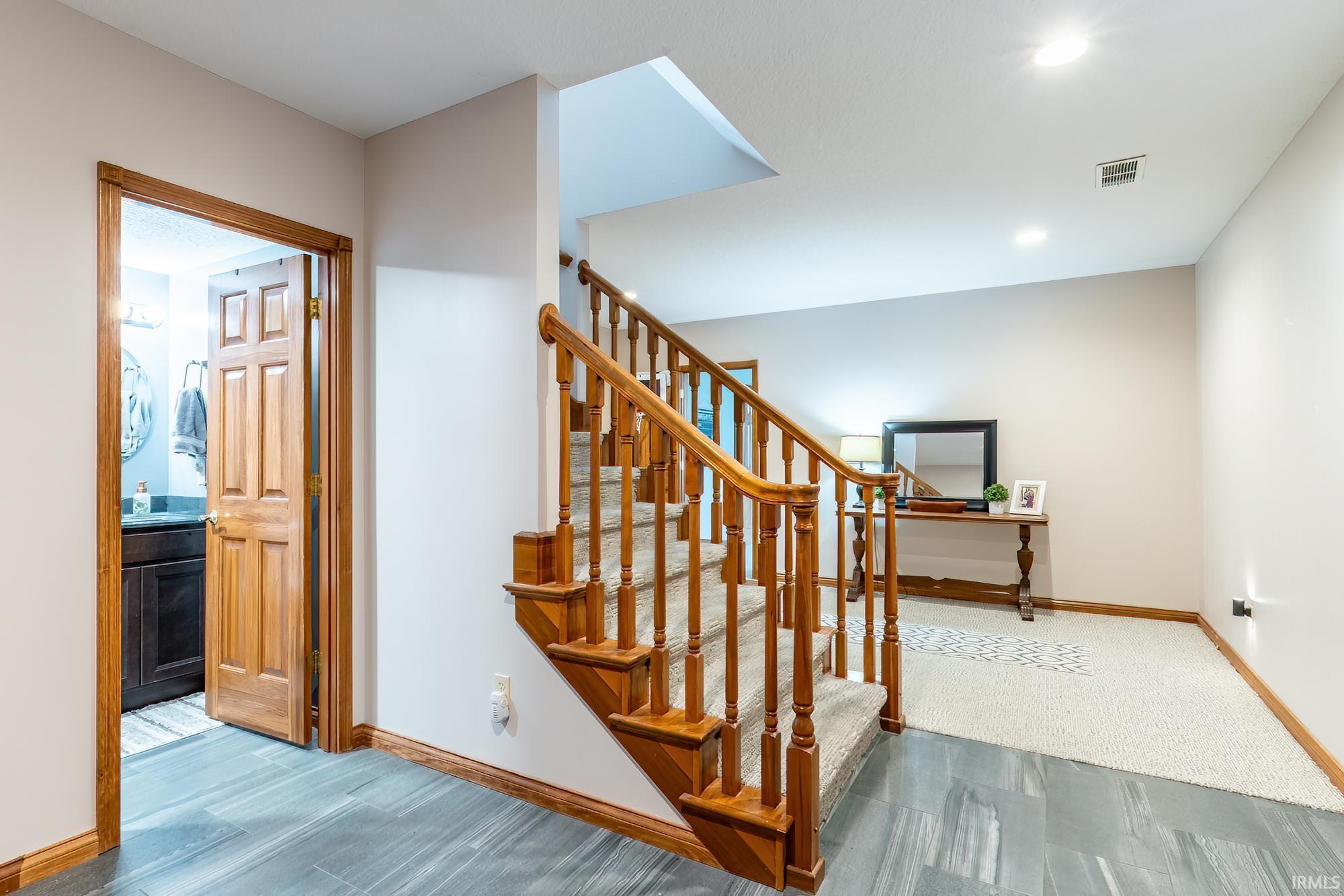 Hardwood staircase with carpeted treads, wood-finish flooring, and recessed lighting