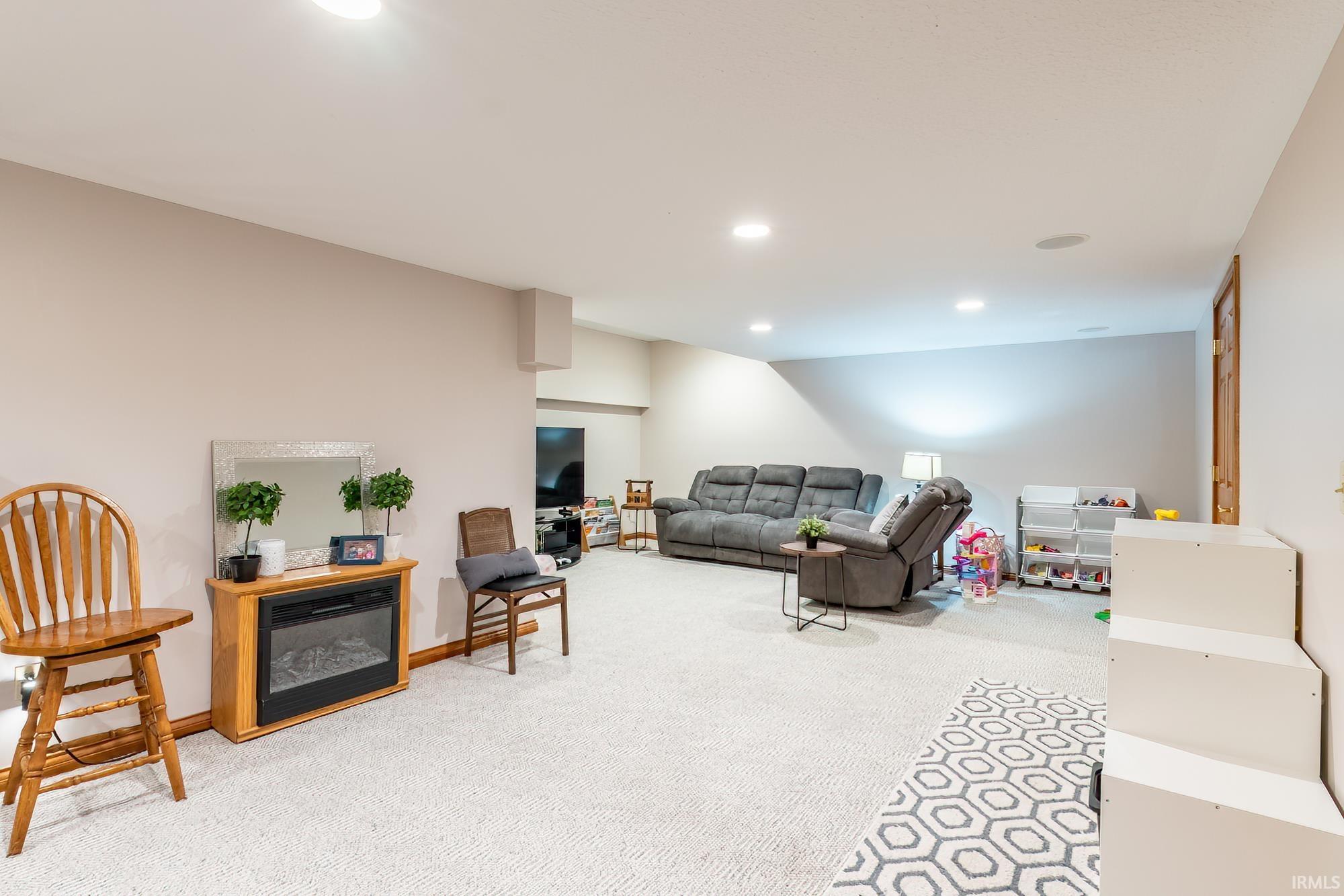 Recessed lighting, wood-finish trim, light-colored carpeting, and an integrated electric fireplace