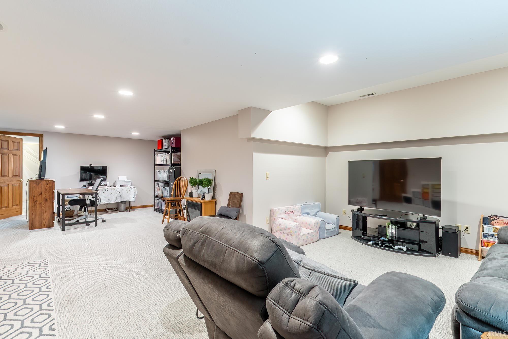 Recessed lighting illuminates the carpeted flooring and light-toned walls