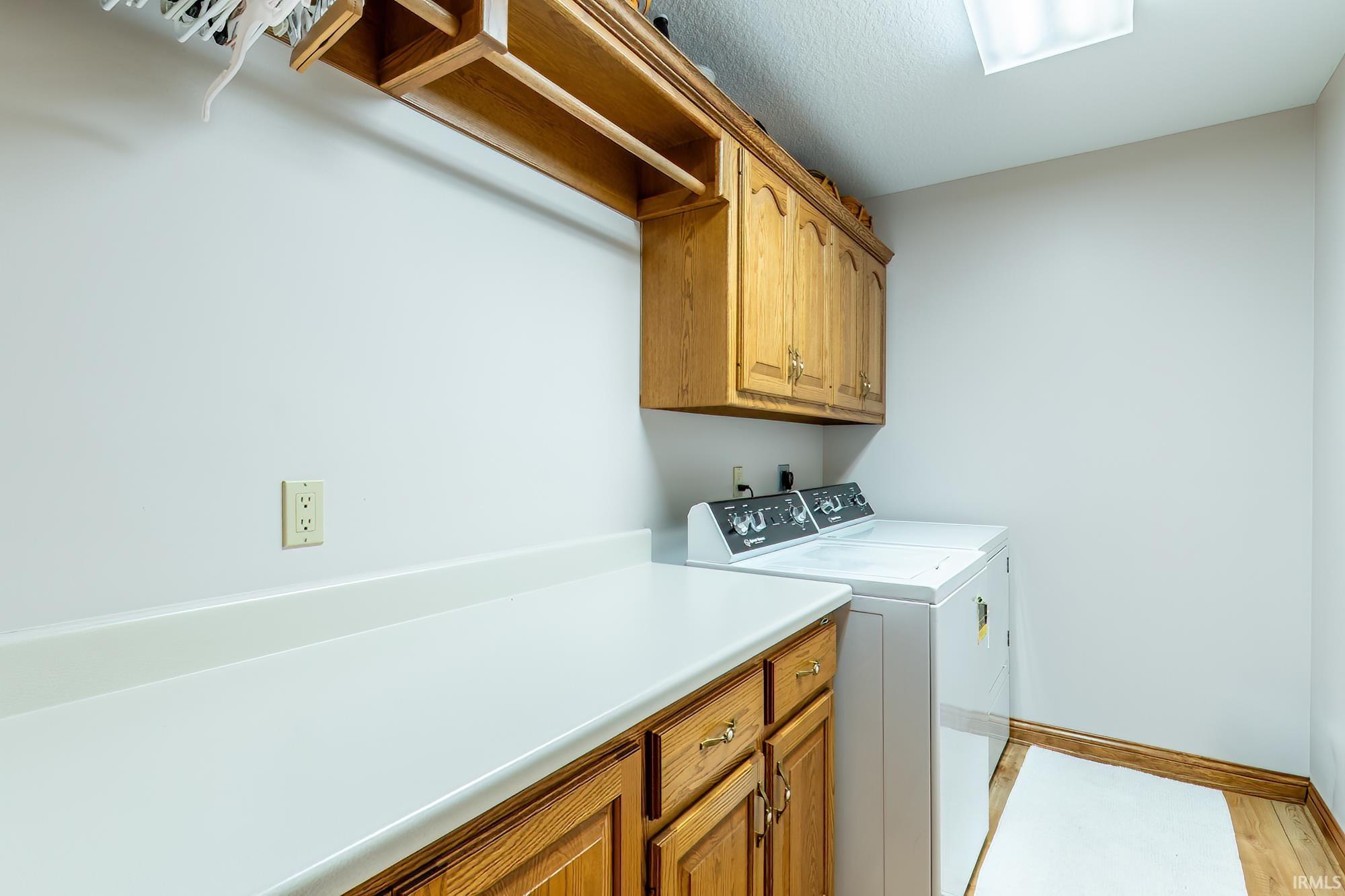 Laundry area featuring wood-finish cabinetry, a white countertop, and wood-finish flooring