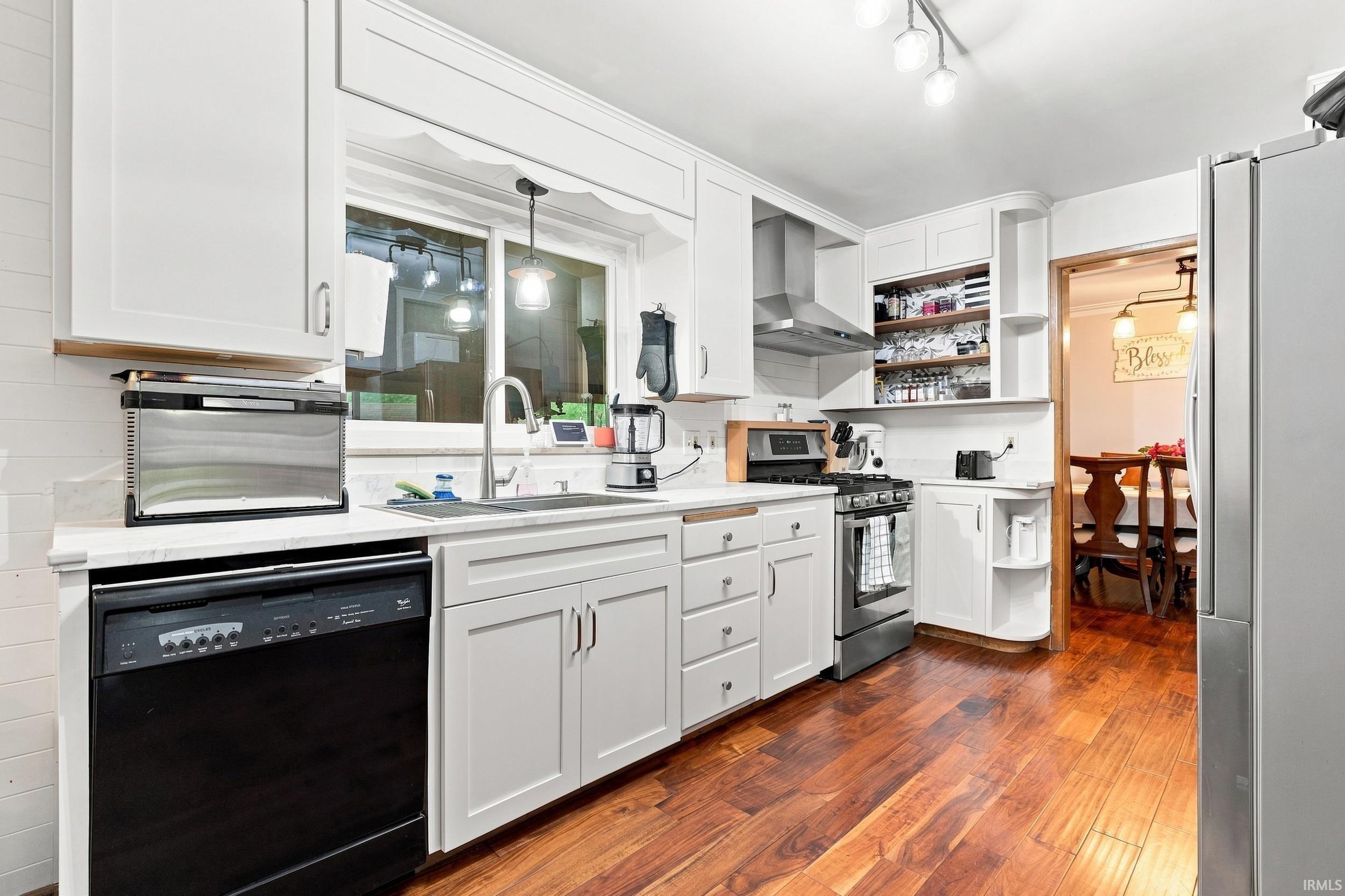 White cabinetry with chrome hardware, stainless steel appliances, wood-finish flooring, white countertops, and a stainless steel sink with a gooseneck faucet
