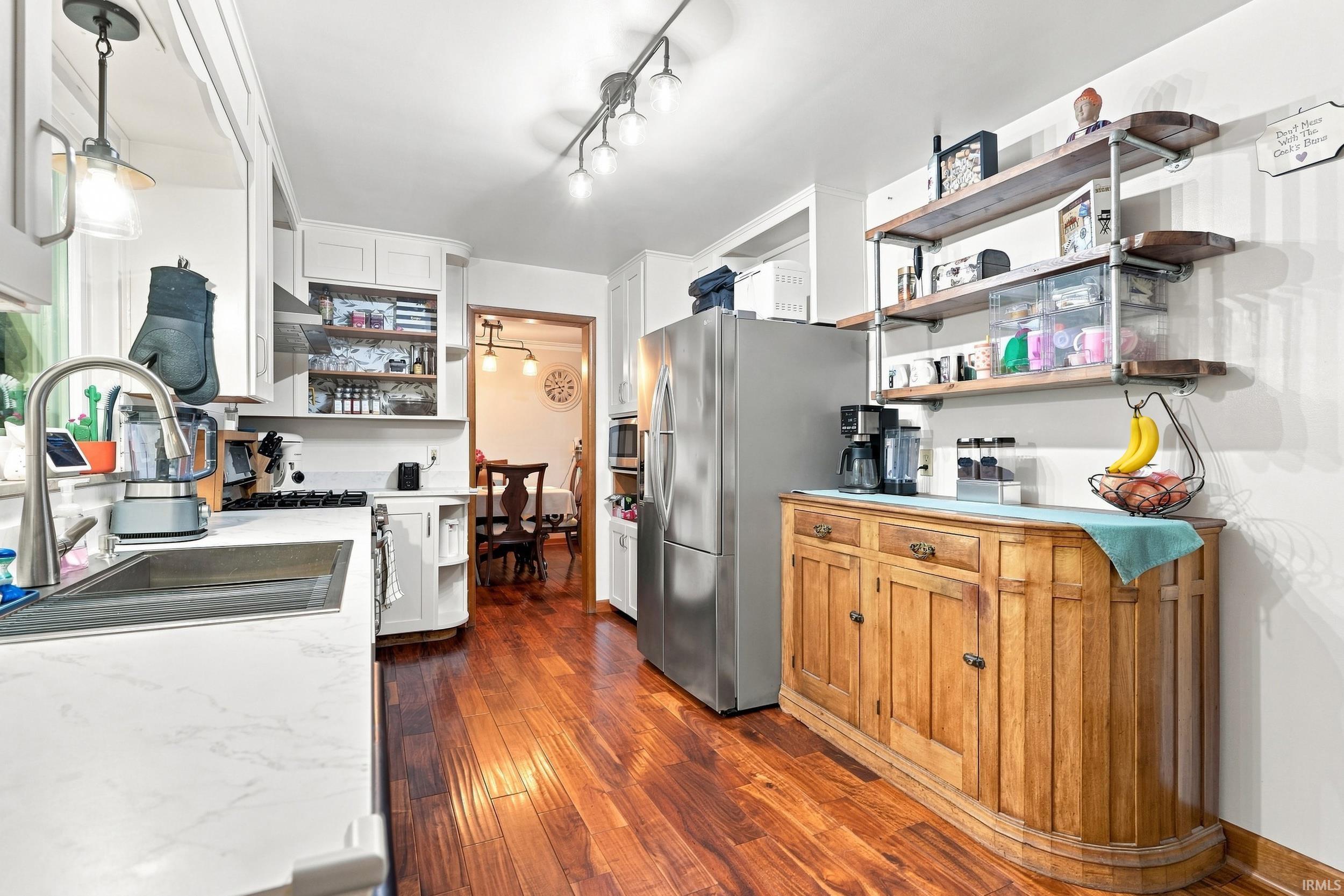 Kitchen featuring wood-finish flooring, white cabinetry, a stainless steel sink, and track lighting